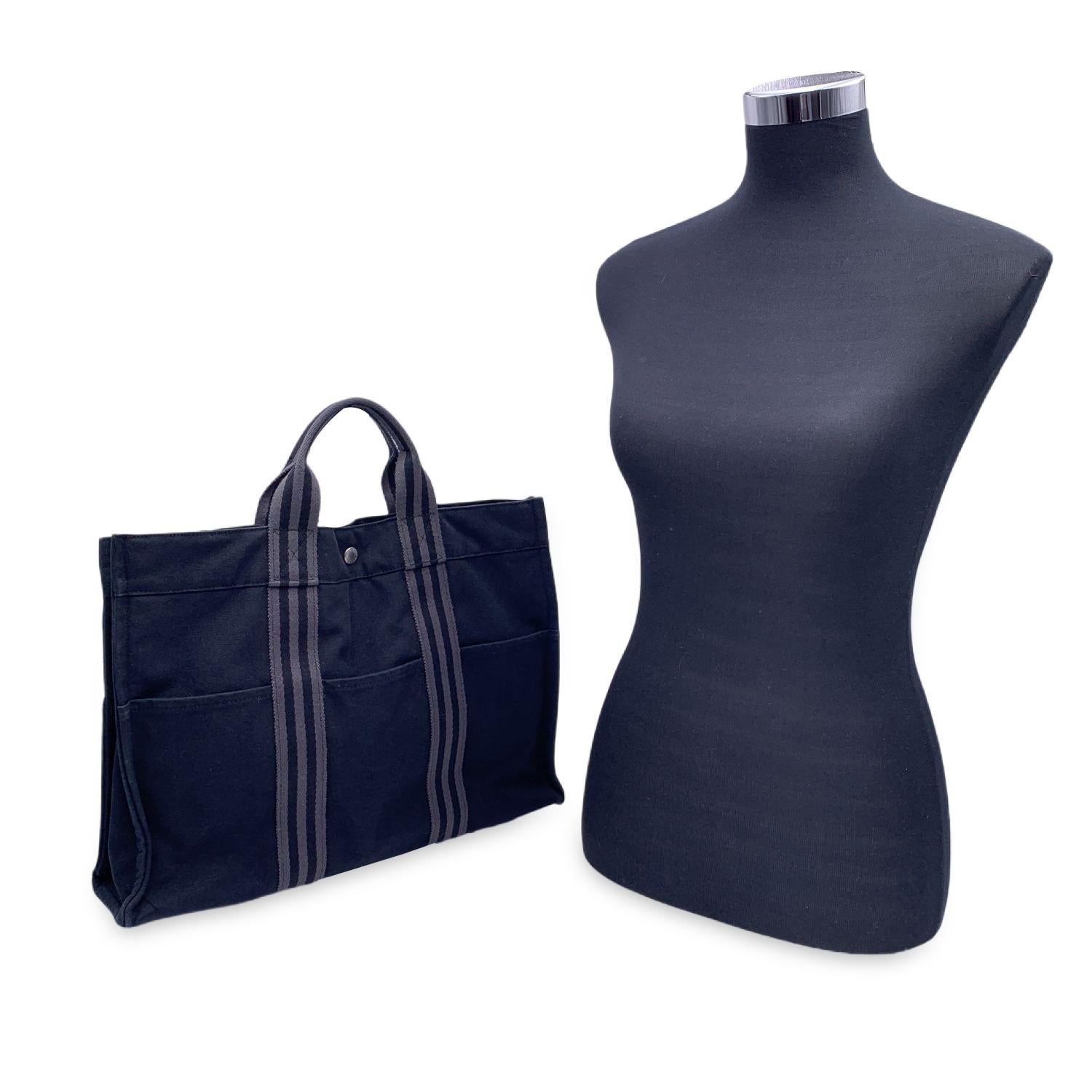 'HERMES FOURRE TOUT - MM' - Tote handbag. Made in France. Black color with grey stripes. Material: 100% cotton. It has snaps on both ends for expansion. Durable canvas handles, perfect for casual and everyday use. 3 open pockets on the front and 3