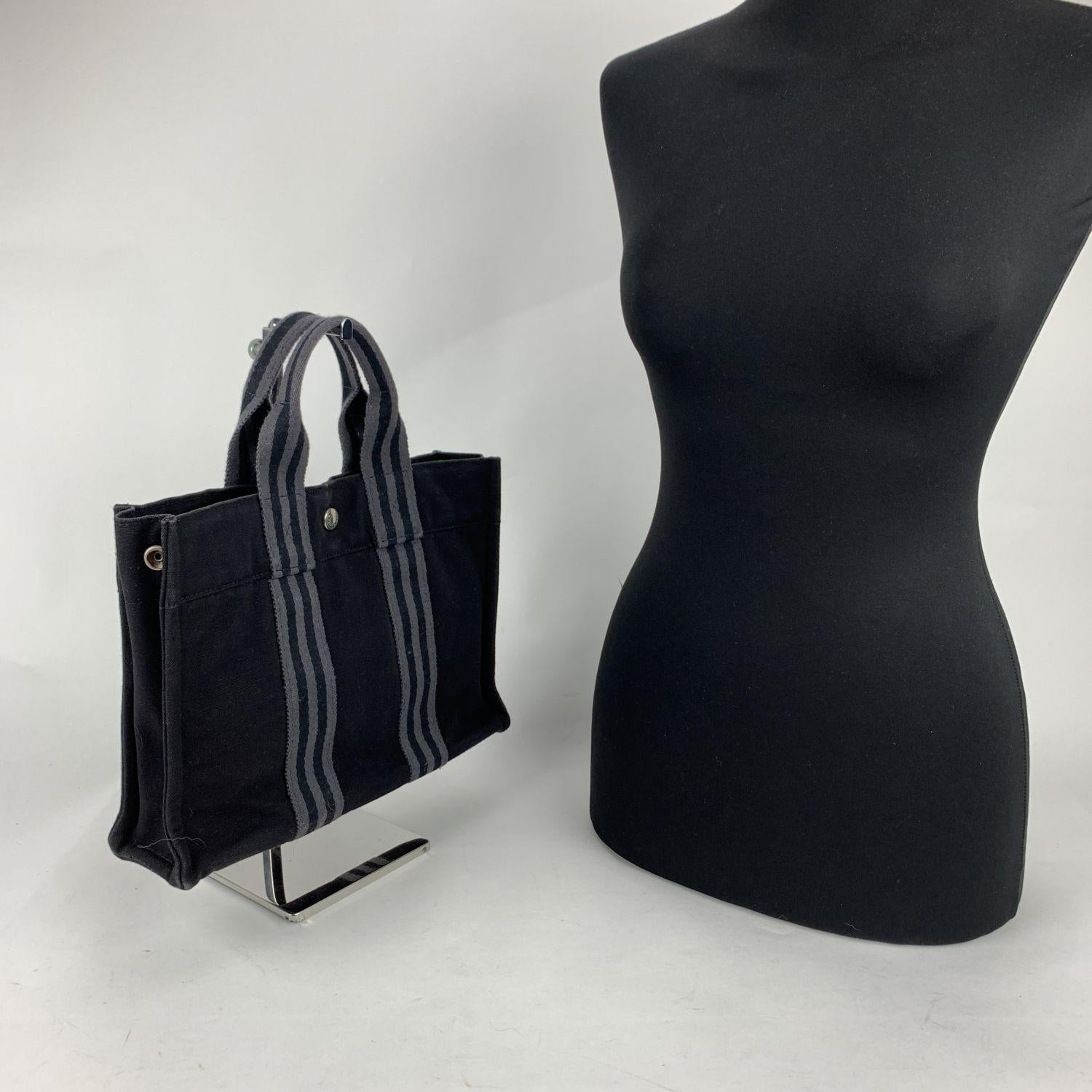 Model: 'HERMES FOURRE TOUT - PM' Tote handbag. Made in France. Black color with grey stripes. Material: 100% cotton. It has snaps on both ends for expansion. Durable canvas handles, perfect for casual and everyday use. Open top with middle snap
