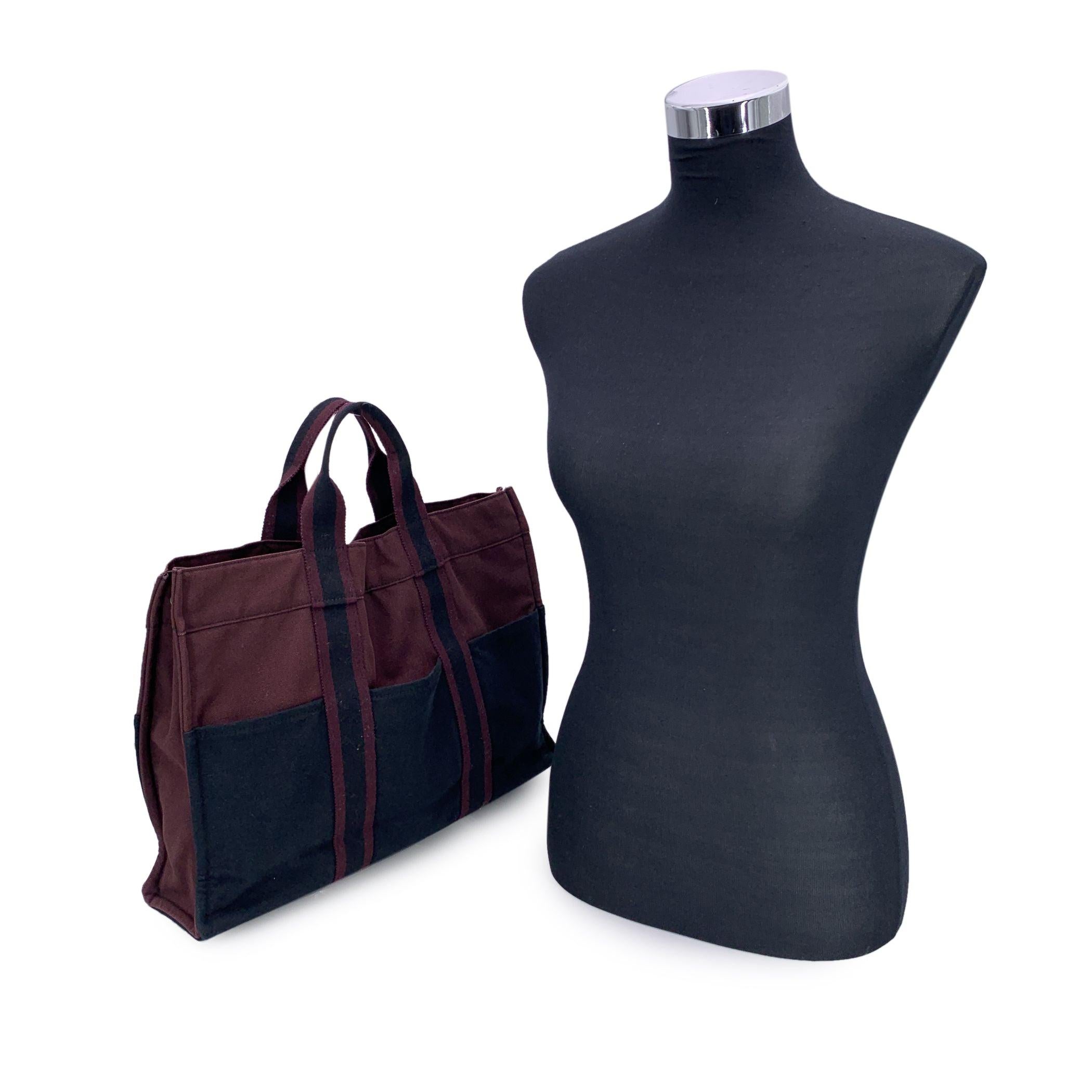 HERMES FOURRE TOUT - MM' - Tote handbag. Made in France. Black color with Burgundy. Material: 100% cotton. It has snaps on both ends for expansion. Durable canvas handles, perfect for casual and everyday use. 3 open pockets on the front and 3 open