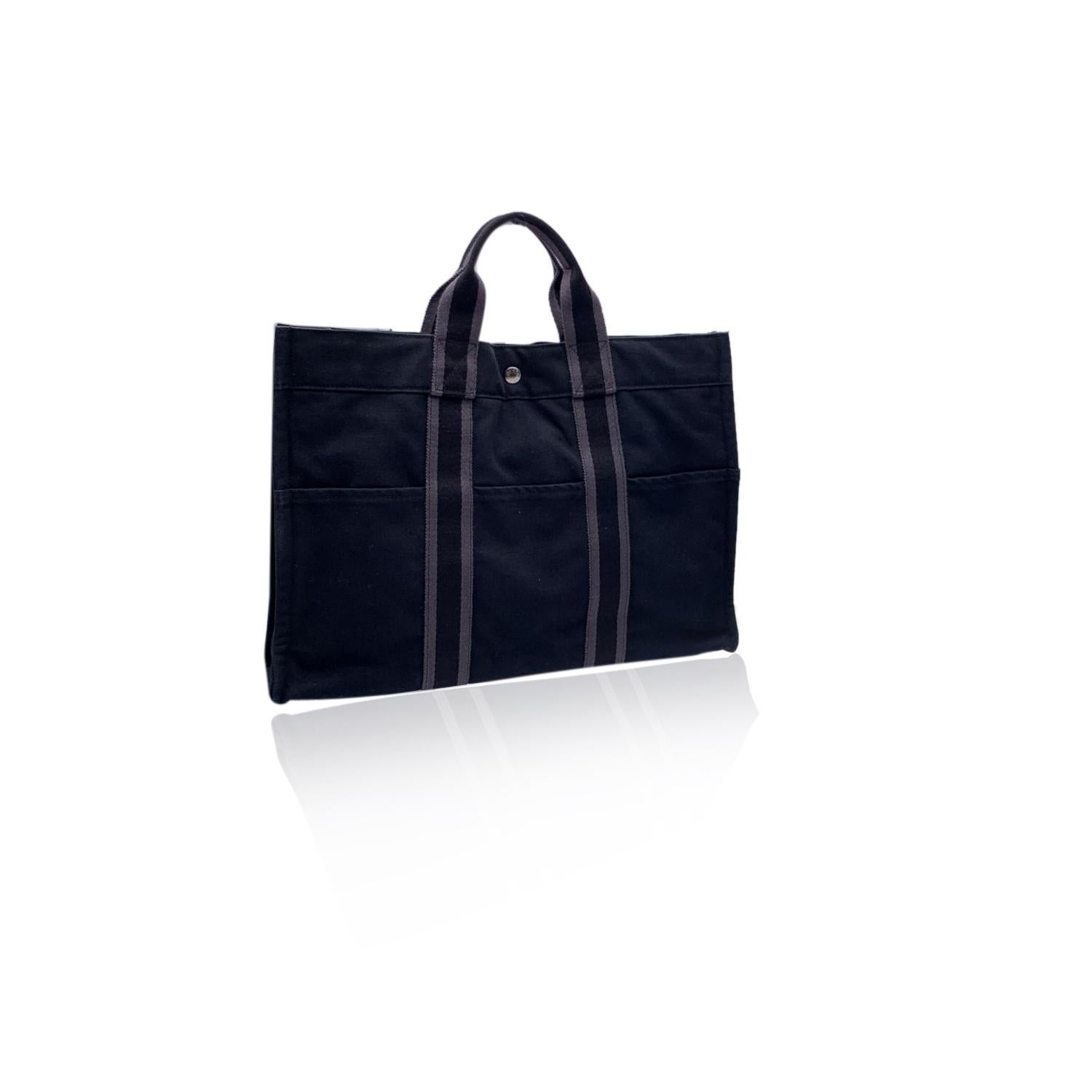  'HERMES FOURRE TOUT - MM' - Tote handbag. Made in France. Black color with grey stripes. Material: 100% cotton. It has snaps on both ends for expansion. Durable canvas  handles, perfect for casual and everyday use. 3 open pockets on the front and 3