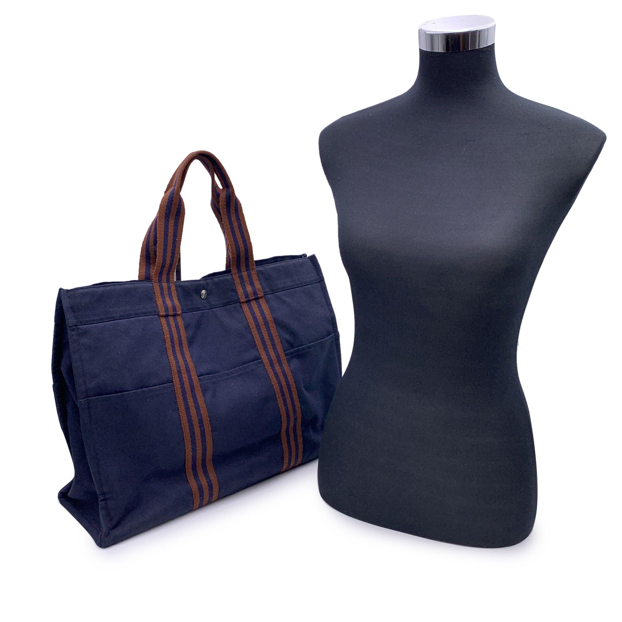 HERMES FOURRE TOUT - GM' - Tote handbag. Made in France. Blue color with brown stripes. Material: 100% cotton. It has snaps on both ends for expansion. Durable canvas handles, perfect for casual and everyday use. 3 open pockets on the front and 3