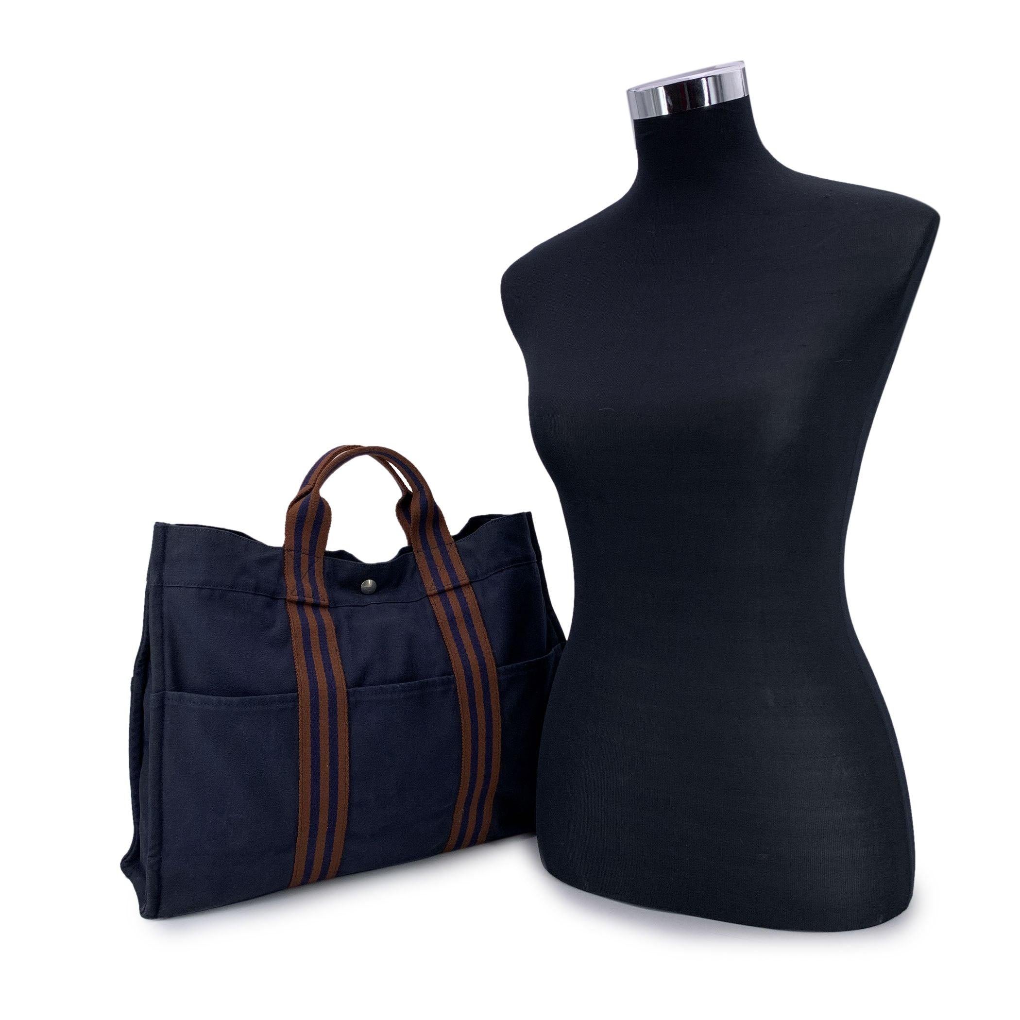 HERMES FOURRE TOUT - MM' - Tote handbag. Made in France. Navy Blue color with brown stripes. Material: 100% cotton. It has snaps on both ends for expansion. Durable canvas handles, perfect for casual and everyday use. 3 open pockets on the front and
