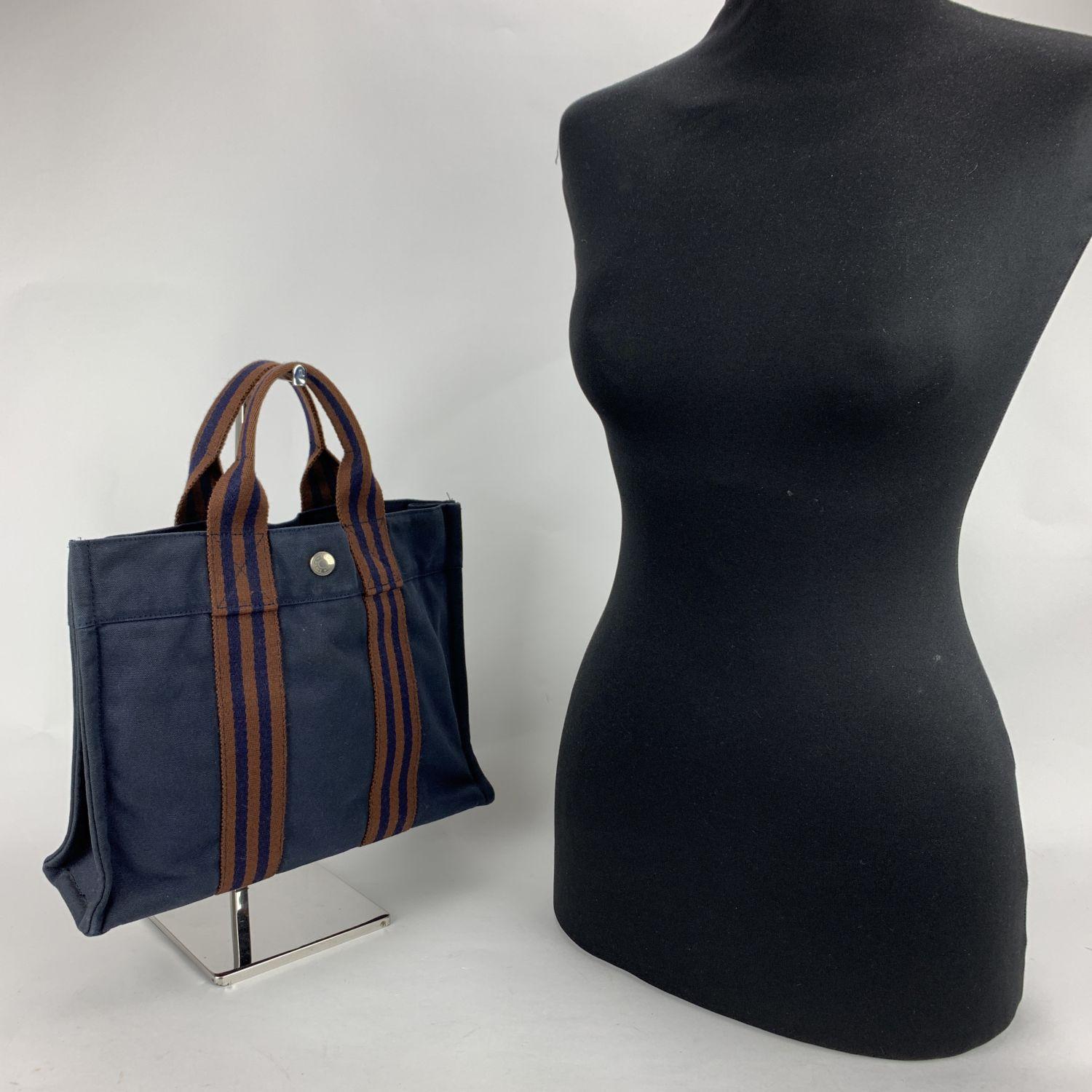 Model: 'HERMES FOURRE TOUT - PM' Tote handbag. Made in France. Blue color with brown stripes. Material: 100% cotton. It has snaps on both ends for expansion. Durable canvas handles, perfect for casual and everyday use. Open top with middle snap