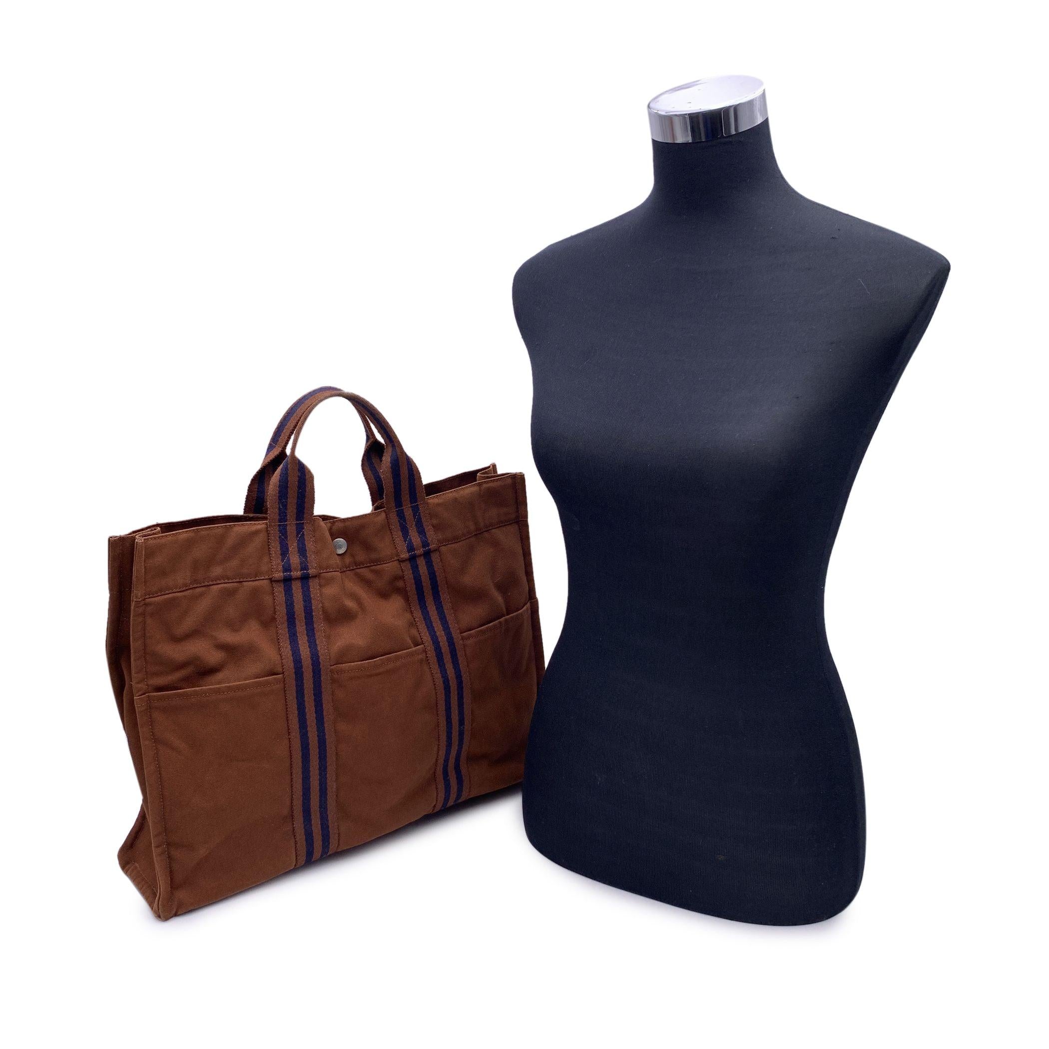 Hermes Paris Vintage brown cotton canvas tote, Fourre Tout MM. Made in France. Blue stripes. 100% Cotton. 3 front pockets on the front and 3 pockets on the back. It has snaps (buttons) on both ends for expansion. Durable canvas handles, perfect for