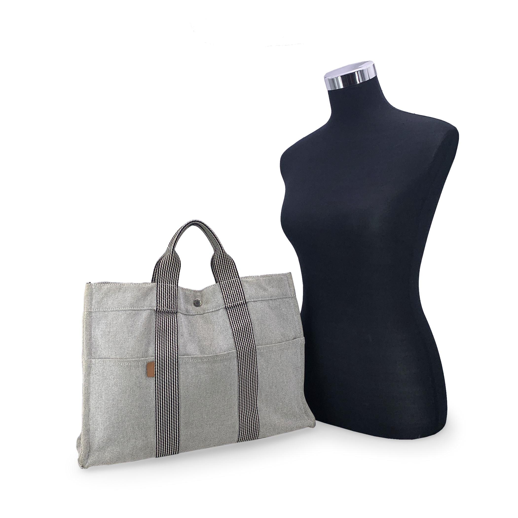 Hermes Paris Vintage light grey cotton canvas tote, Fourre Tout MM. Made in France. Black contrast stripes. 100% Cotton. 3 front pockets on the front and 3 pockets on the back. It has snaps (buttons) on both ends for expansion. Durable canvas