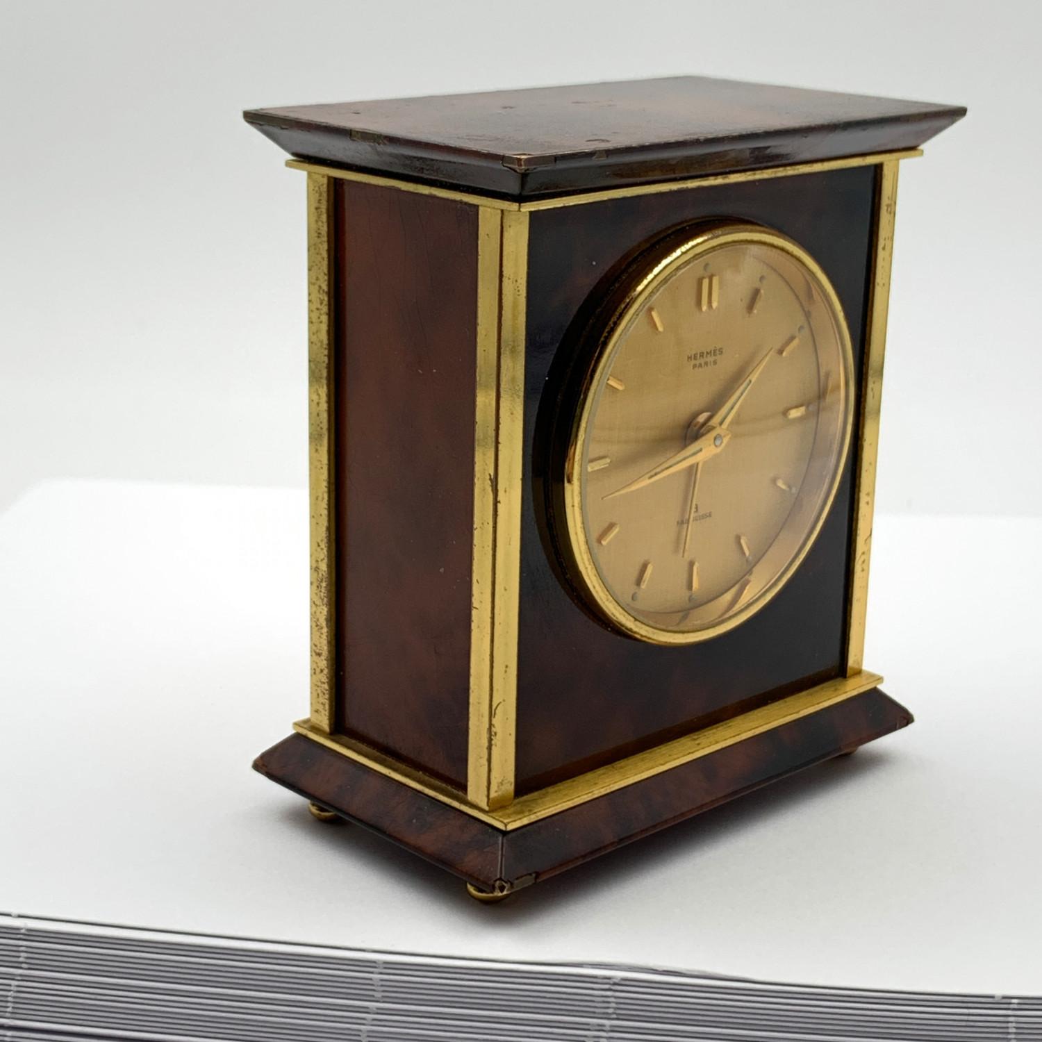 Hermes alarm travel clock, mod. 1227, from the '70s. Made in brown marbled metal with gold plated metal detailing and markers. It is marked 'Hermes Paris' and 'Fab. Suisse' on the dial. Mechanical movement. Height: 3 inches - 7.6 cm. Width: 3 inches