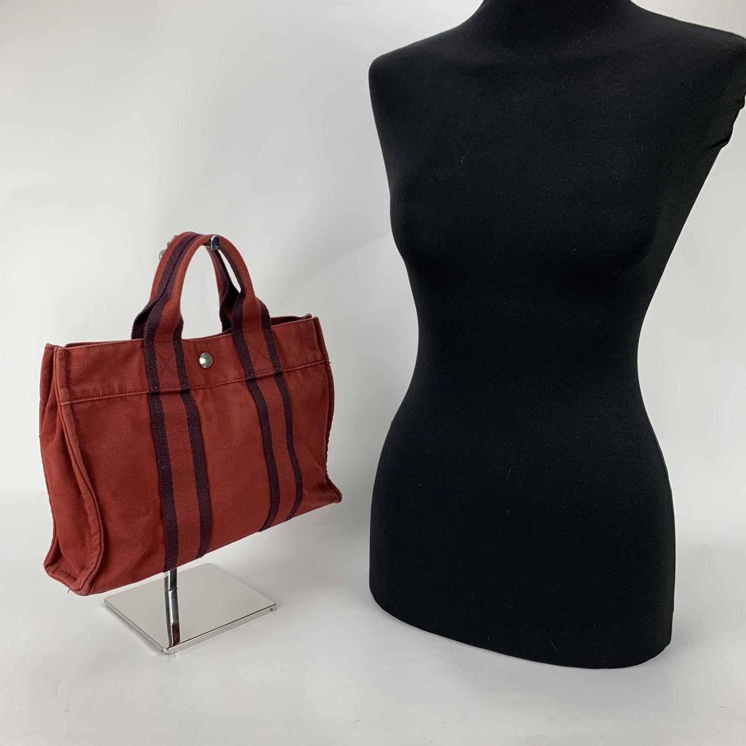 Model: 'HERMES FOURRE TOUT - PM' Tote handbag. Made in France. Red color with blue stripes. Material: 100% cotton. It has snaps on both ends for expansion. Durable canvas handles, perfect for casual and everyday use. Open top with middle snap