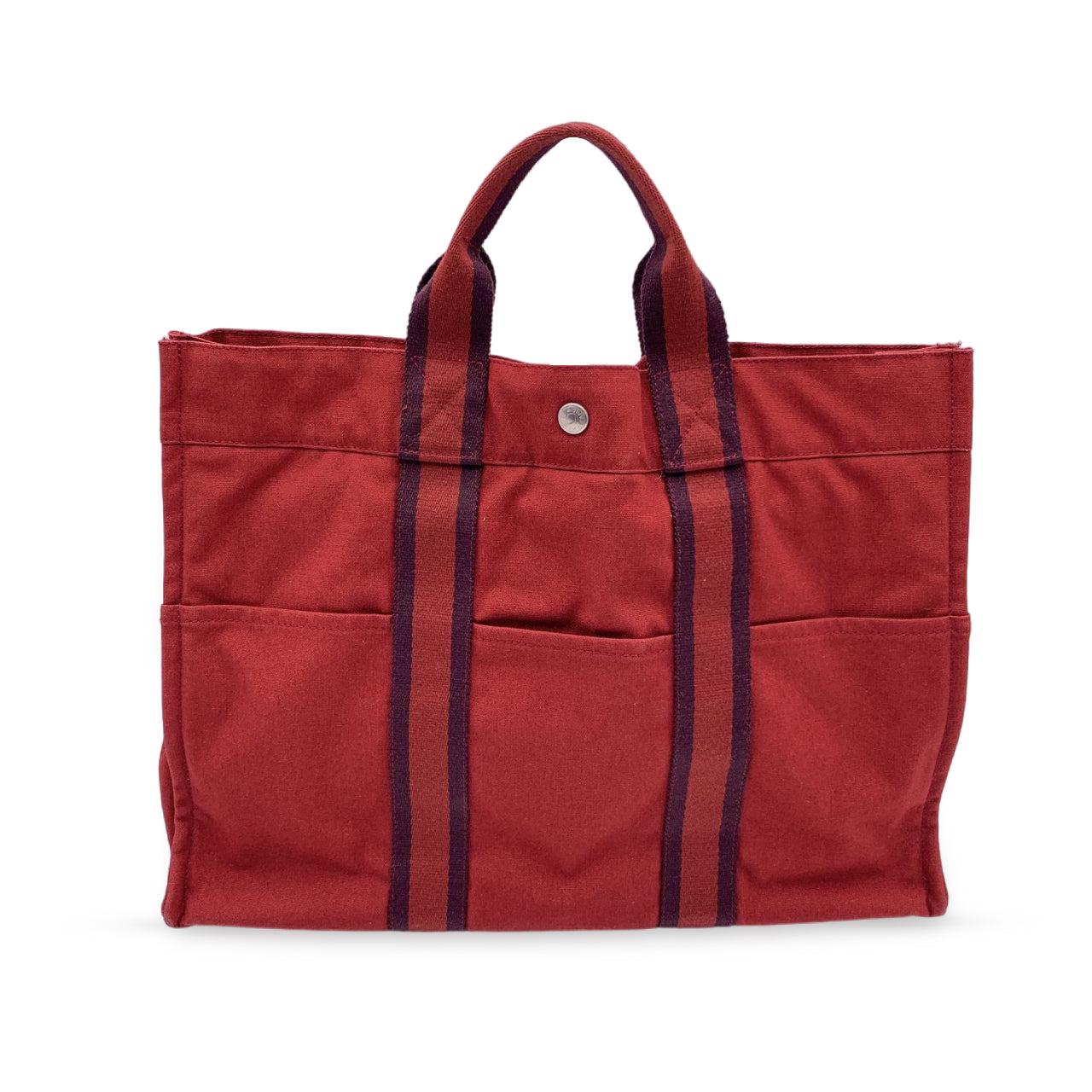 Hermes Paris Vintage red cotton canvas tote, Fourre Tout MM. Made in France. Red color with contrast stripes. 100% Cotton. 3 front pockets on the front and 3 pockets on the back. It has snaps (buttons) on both ends for expansion. Durable canvas