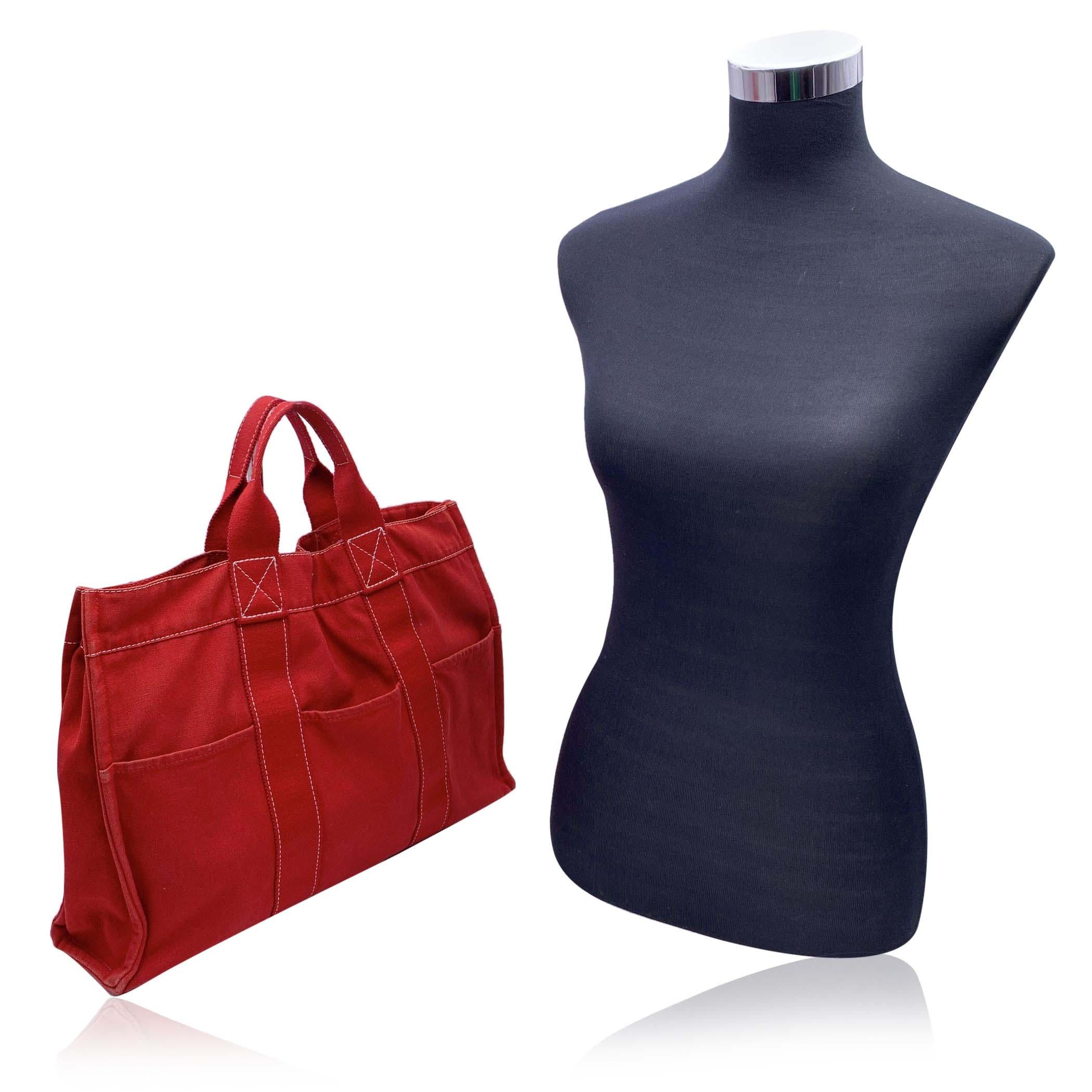 Hermes Paris Vintage red cotton canvas tote, Fourre Tout MM. Made in France. Red color with white contrast stitchings. 100% Cotton. 3 front pockets on the front and 3 pockets on the back. It has snaps (buttons) on both ends for expansion. Durable