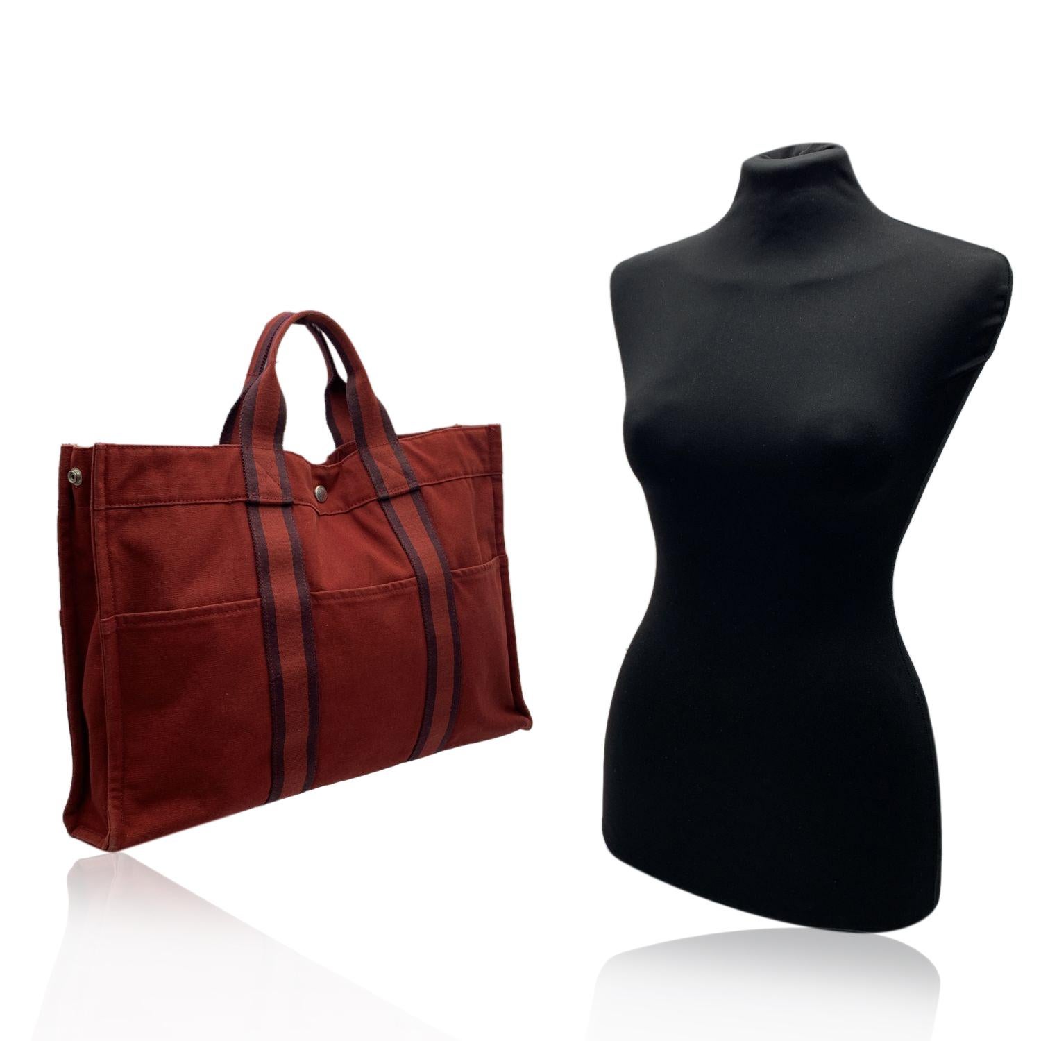 'HERMES FOURRE TOUT - MM' - Tote handbag. Made in France. Brown/burgundy color with red stripes. Material: 100% cotton. It has snaps on both ends for expansion. Durable canvas handles, perfect for casual and everyday use. Open top with middle snap