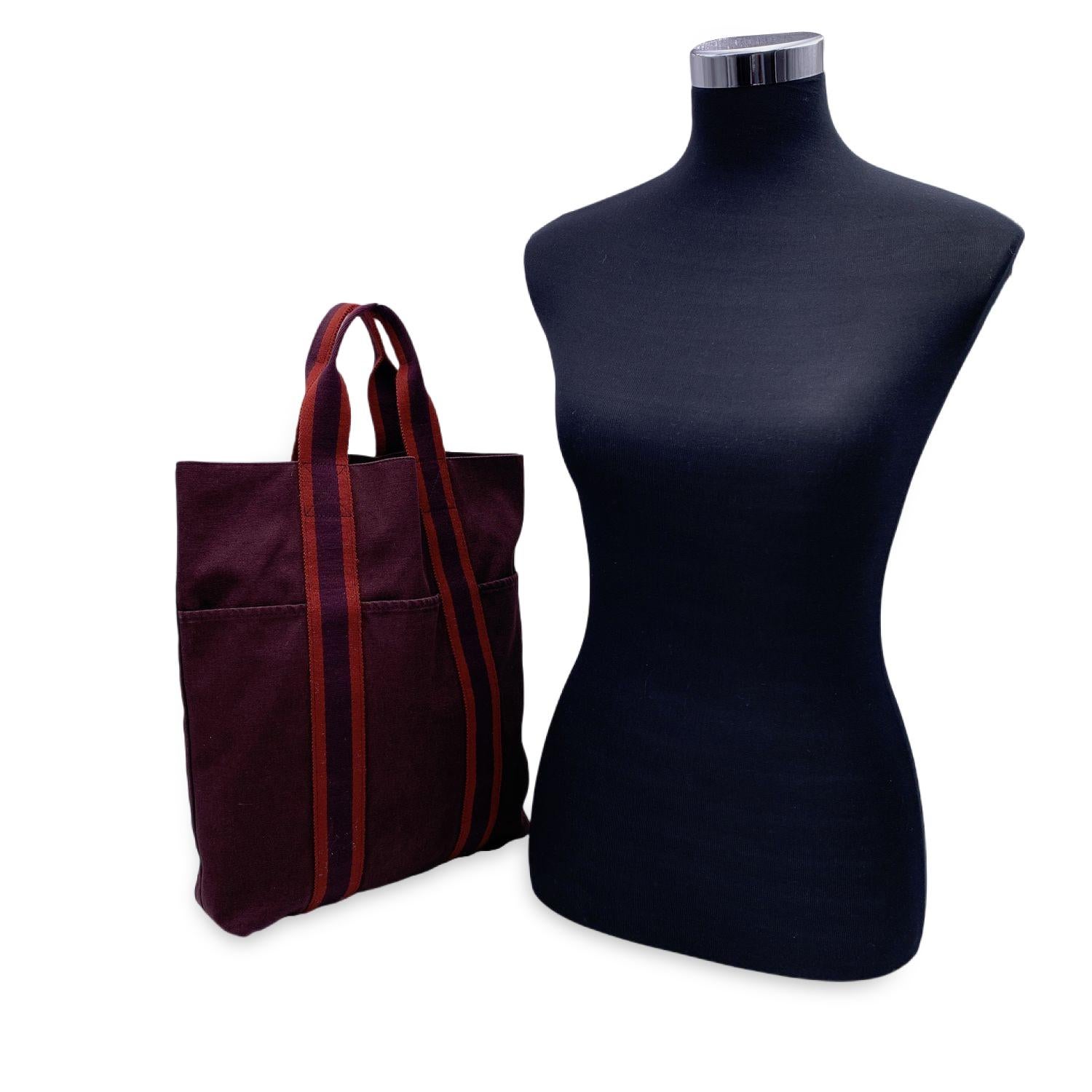 Model: 'HERMES Vertical FOURRE TOUT ' Shopping Bag. Made in France. Brown/burgundy color with red stripes. Material: 100% cotton. Durable canvas handles, perfect for casual and everyday use. Open top. 3 open pockets on the front Canvas internal