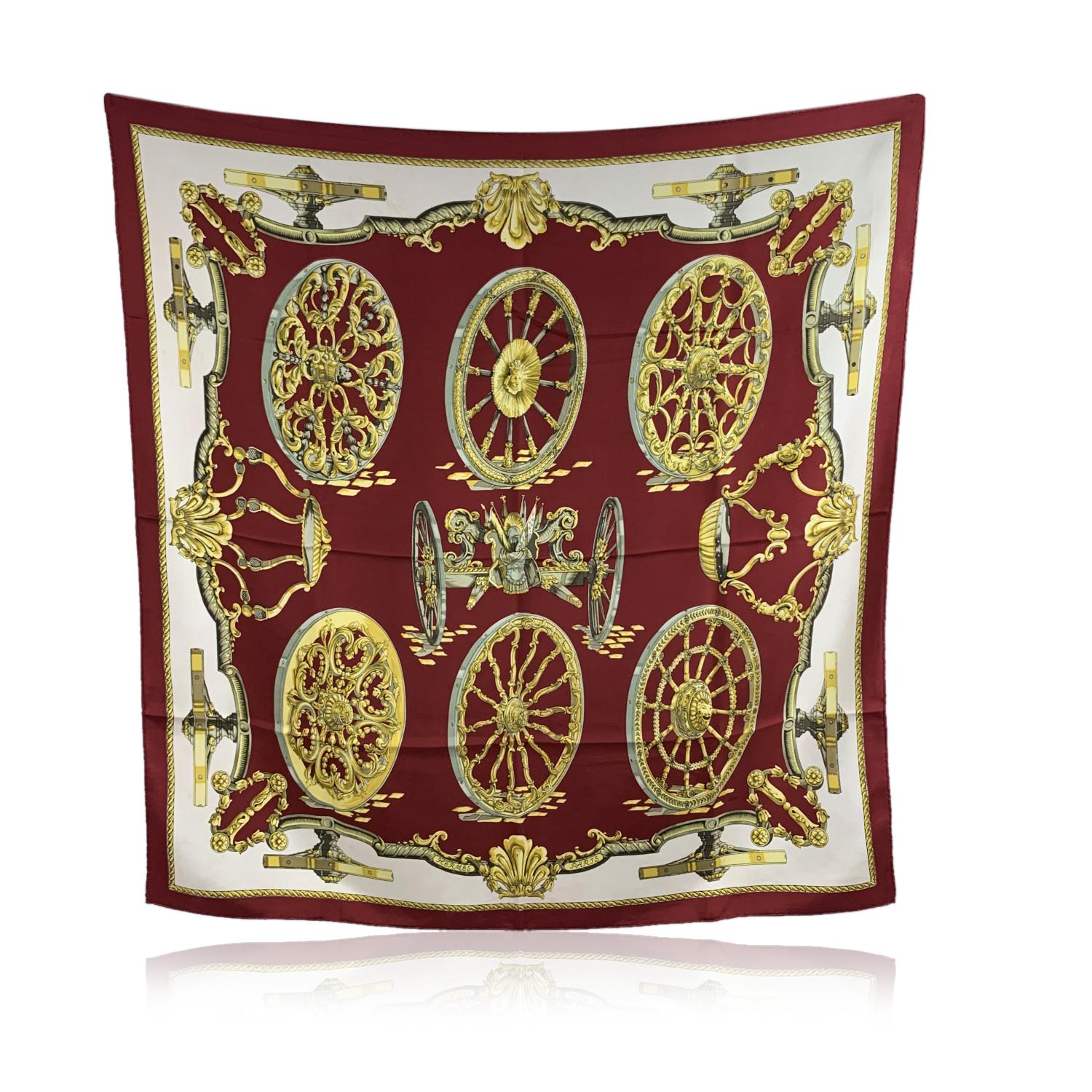 HERMES Silk scarf named 'Roues de Canon', created by artist Caty Latham, and first issued in 1967. It depicts different types of cannon wheels. Main colors are burgundy, white, and yellow. 100% Silk. Hand rolled edges. Approx measurements: 35 x 35