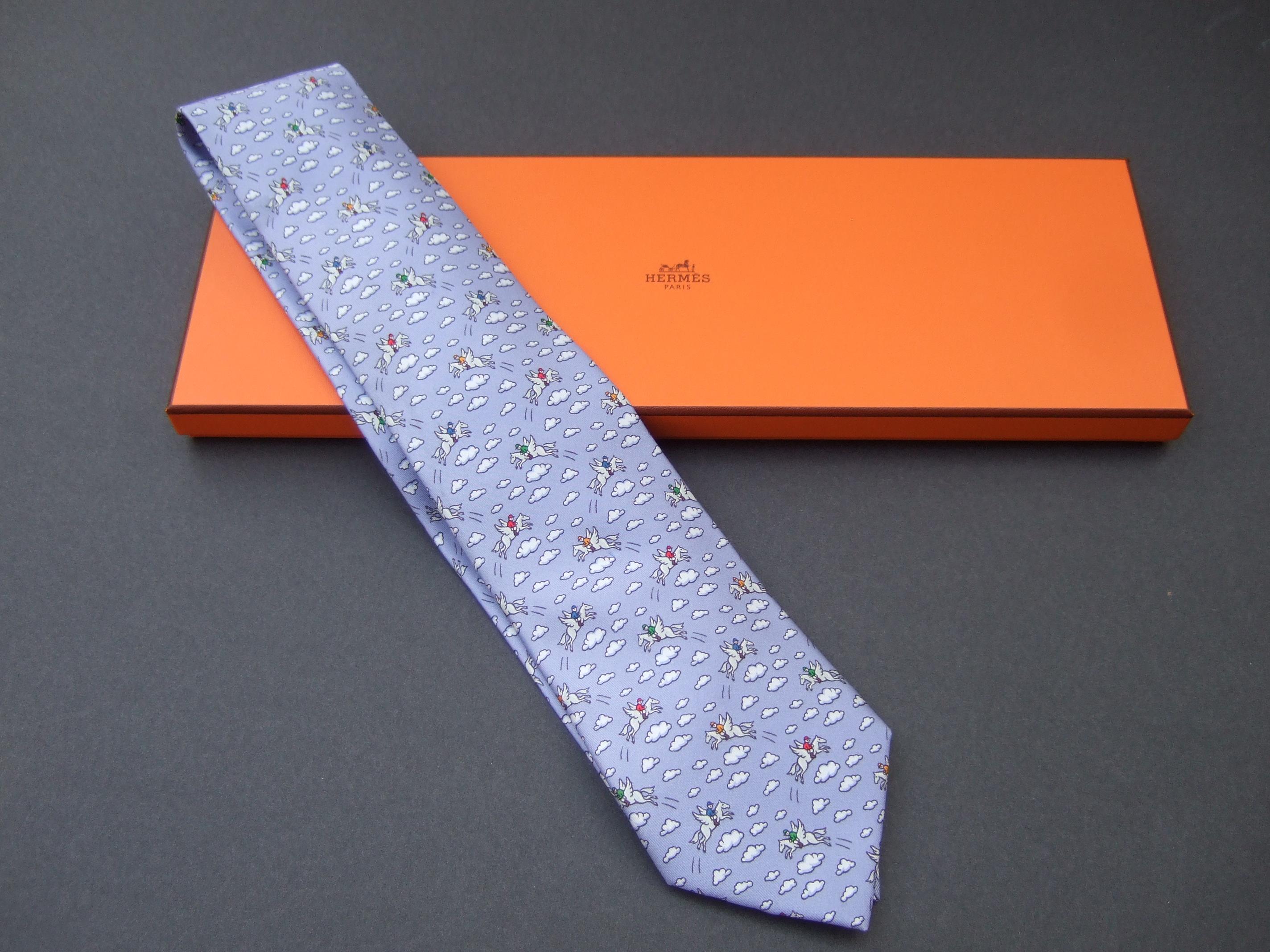 Hermes Paris whimsical silk flying pegasus rider necktie in Hermes box c 1990s 
The charming necktie is illuminated with a sky blue background 
with a series of billowy clouds 

Makes a stylish fun accessory

The widest section of the necktie