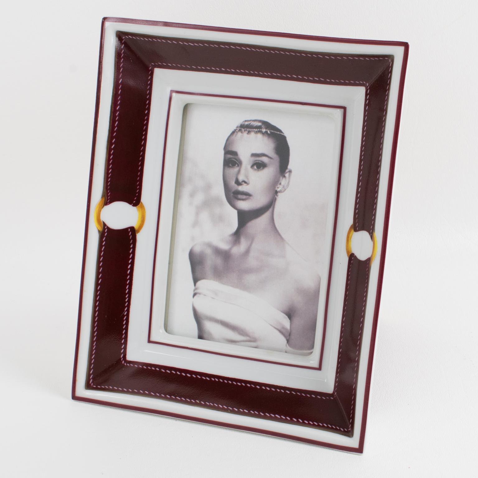 Hermes, Paris designs this superb and rare picture photo frame. Exclusively made for Hermes in Limoges, this timeless and elegant white porcelain picture frame is hand-decorated with Hermes' iconic buckle and strap in burgundy red and gold colors.