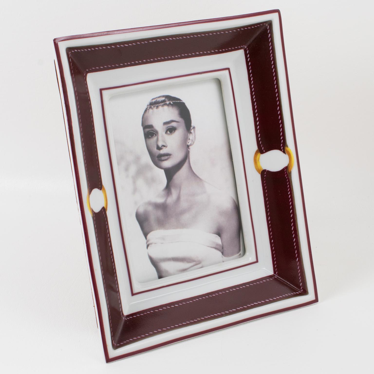 Hermes, Paris designs this superb and rare picture photo frame. Exclusively made for Hermes in Limoges, this timeless and elegant white porcelain picture frame is hand-decorated with Hermes' iconic buckle and strap in burgundy red and gold colors.