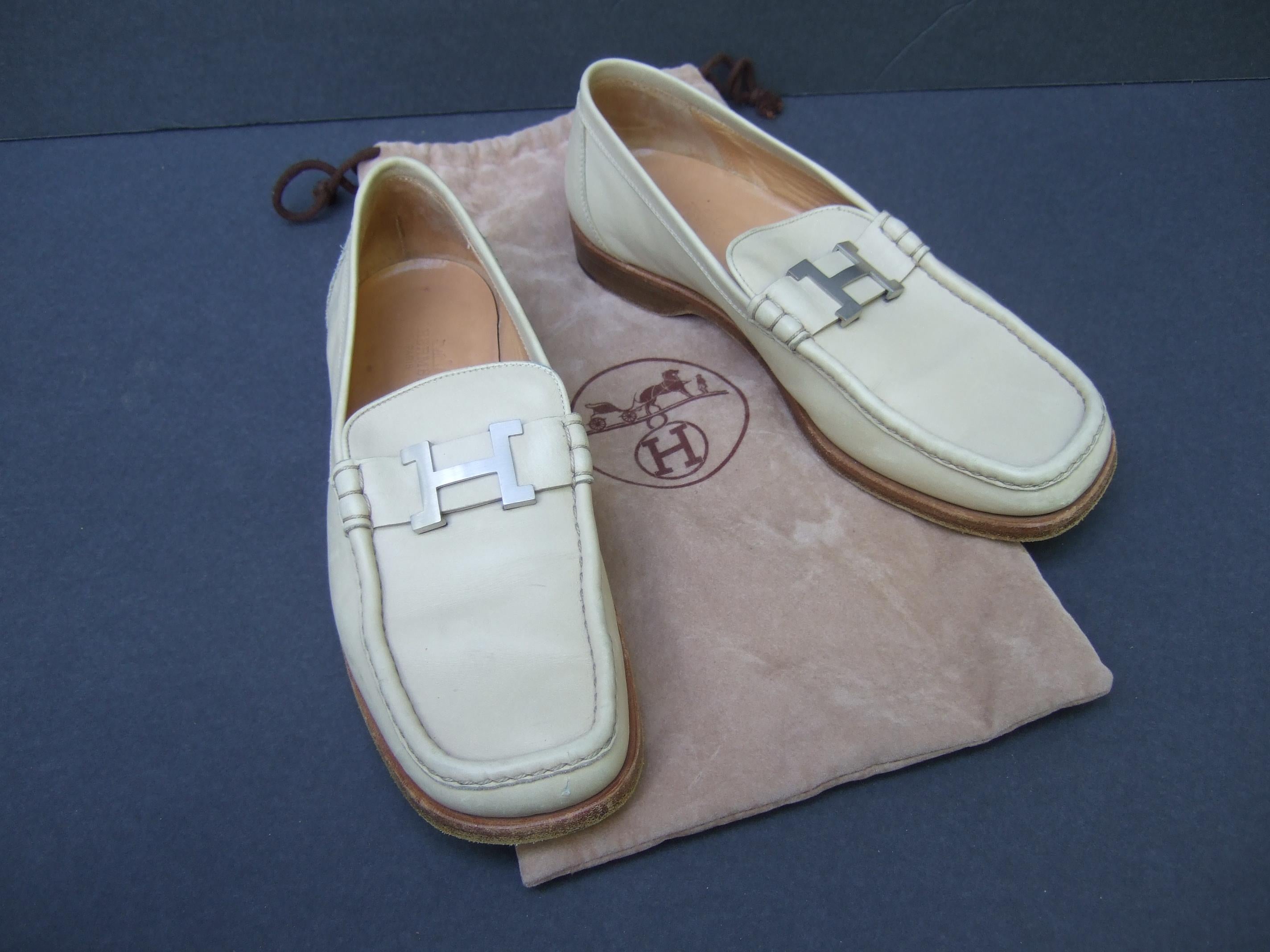 Hermes Paris Women's Constance brushed silver buckle bone leather Italian loafers Size 38
The bone color leather loafers are adorned with Hermes' iconic H initial
Designed with a wood brown low heel 

Makes a chic timeless accessory 
Designed by