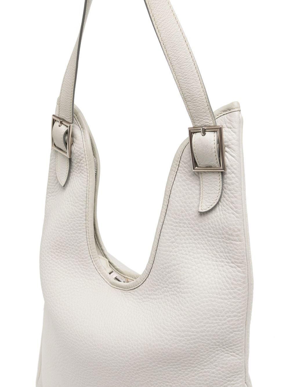 This Hermès Massai PM offers your luxury looks an air of effortless sophistication with its understated slouchy frame and neutral hue. Composed of a Pearl Grey Clemence (grained leather), this exceptional preloved Hermes handbag contrasts its