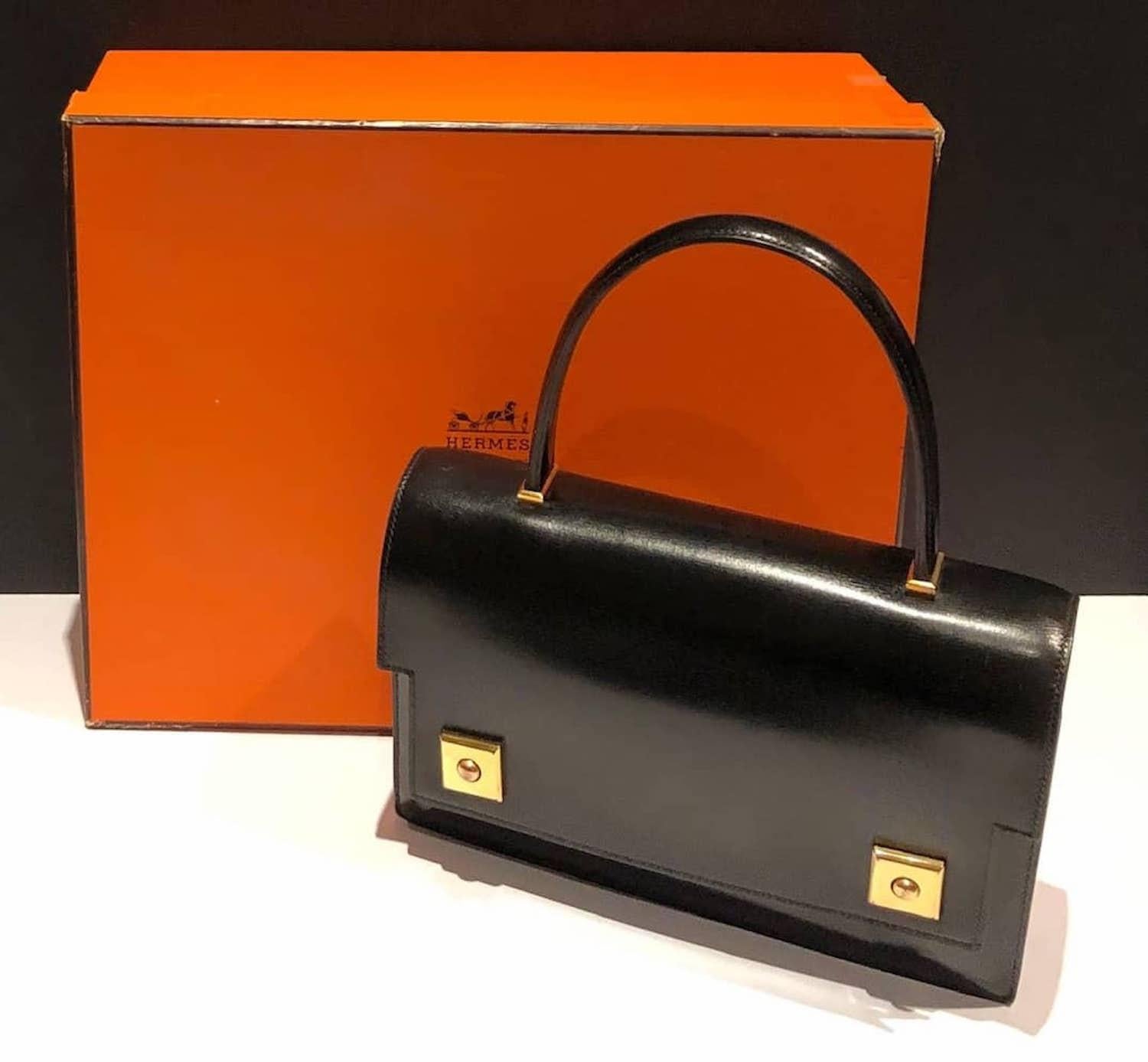 HERMÈS Piano Handbag Black Box Leather Vintage Circa 1960s W/Box
A classic HERMÈS vintage box leather 1968 Piano clasp handbag, in exceptional condition. This beautiful piano bag is handcrafted from black box leather with 18K gold plated hardware.