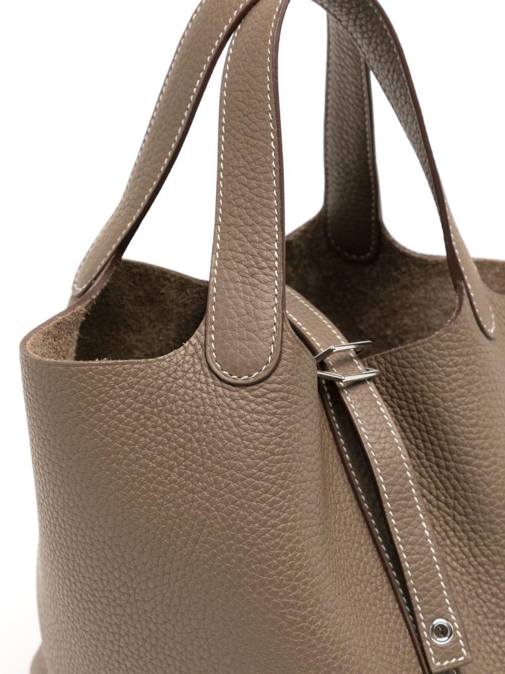 L'élégance intemporelle du sac Picotin 22 Eleg est inégalée. Doté de ferrures en palladium très tendance et d'une couleur étoupe populaire, ce sac de style minimaliste est fabriqué à partir de cuir non doublé et possède des poignées flexibles qui le