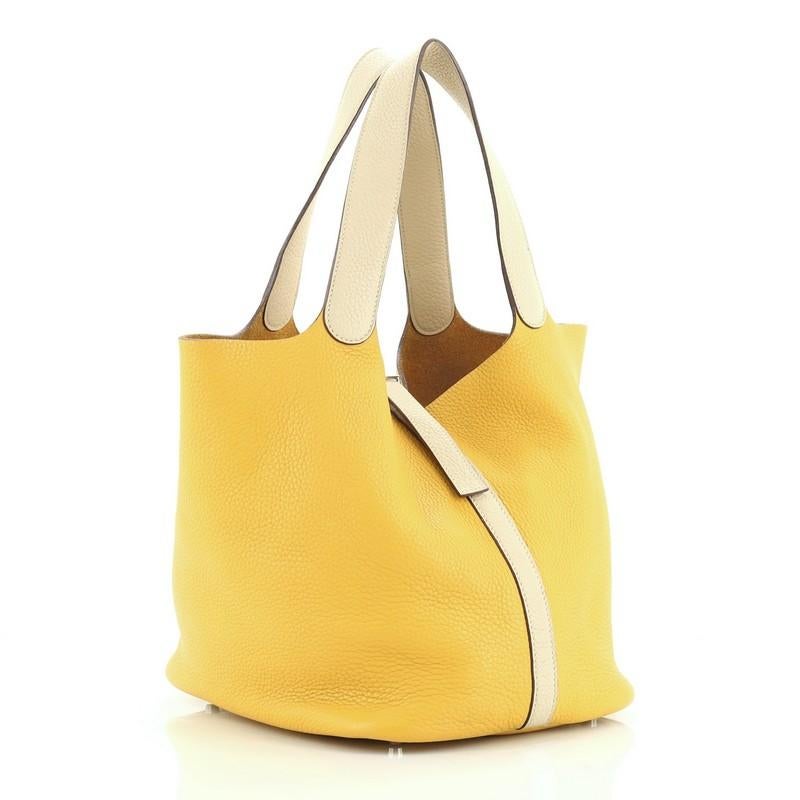 This Hermes Picotin Bag Bicolor Clemence GM, crafted from Soleil and Parchemin Clemence leather, features dual looping leather handles, belt strap with lock closure, and palladium hardware. It opens to a Soleil raw leather interior. Date stamp