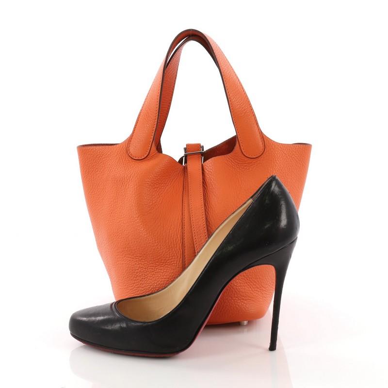 This Hermes Picotin Handbag Togo PM, crafted in Orange H togo leather, features dual looping leather handles, protective base studs and silver-tone hardware. The top strap opens to an orange suede interior. Date stamp reads: G Square (2003) **Note: