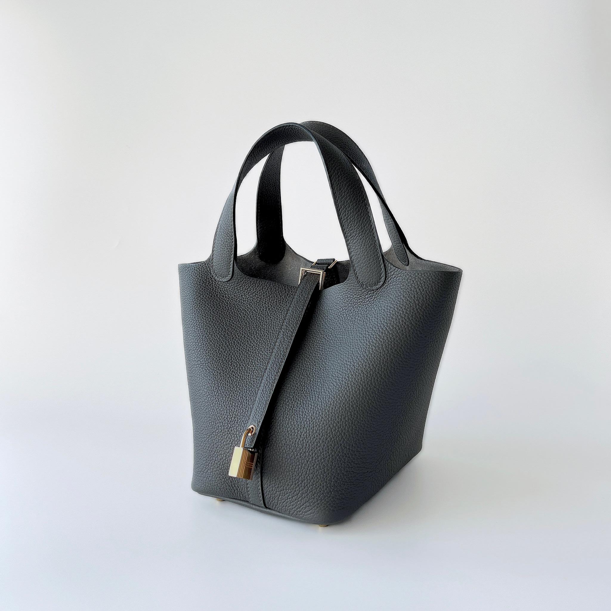 Shop this classic Hermes Picotin 18 which comes in the smaller Picotin size. This Picotin 18 comes in Graphite Grey which is complimented to perfection with Gold Plated Hardware. This bag features 4 gold plated studs which act as feet to prevent