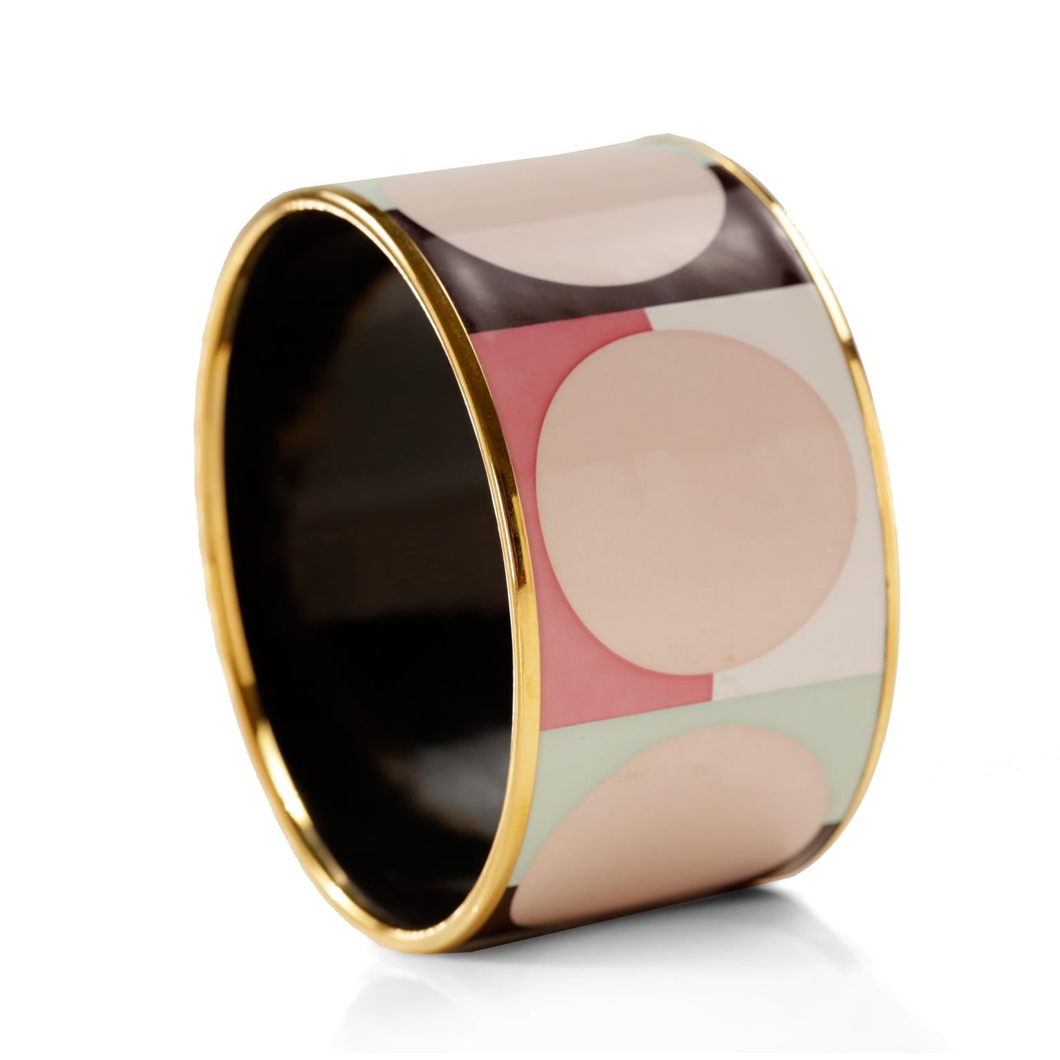 This authentic Hermès Pink Dots Wide Enamel Bracelet is in excellent condition.  Gold tone rim, large pale pink dot design on brown and pastel background. Made in Austria, 2007 production. Approximately 2.75 inch diameter/ 7 cm.

