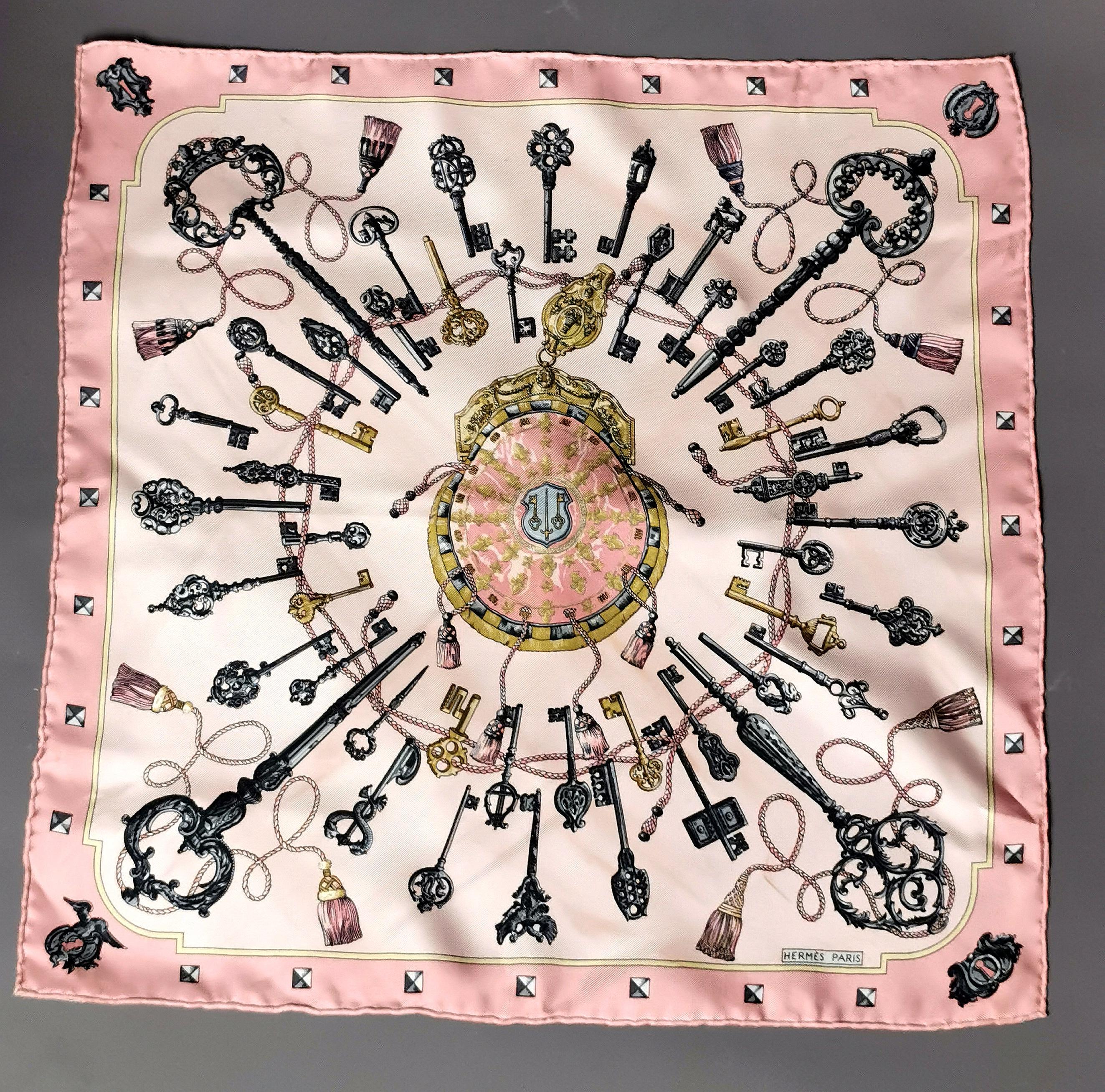 A gorgeous Hermes Keys Les Cles silk scarf in pink.

Pink, white, grey, black and yellow tones can be found within this piece and it is printed with an all over key design.

Made in France from silk, it is marked for Hermes and comes in the original