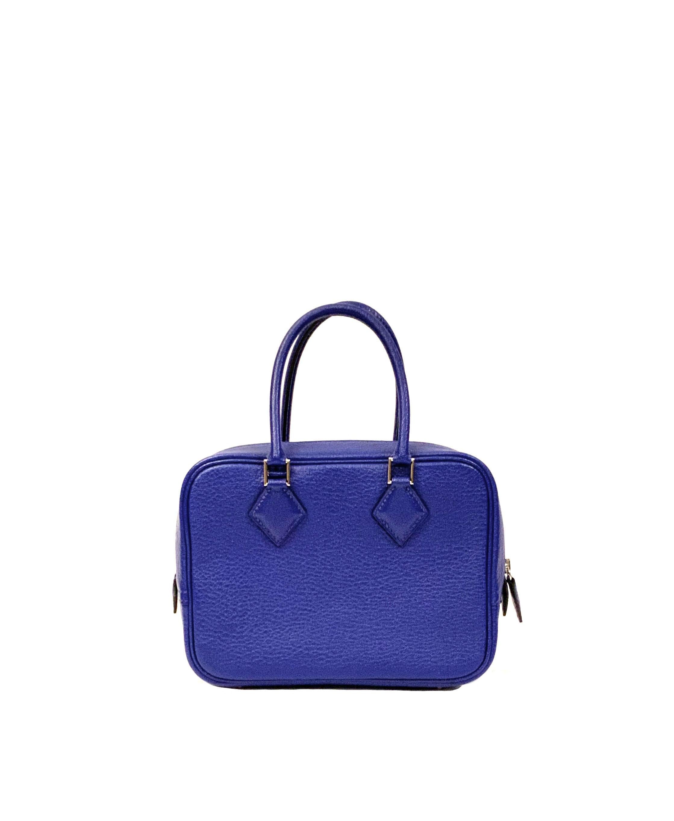 This pre-owned Hermès Plume II mini bag is made of Mysore goatskin leather in a bleu electrique color with palladium plated hardware.
It features a zip closure at the top, two rolled top handles, four bottom feet  and a matching removable bag strap
