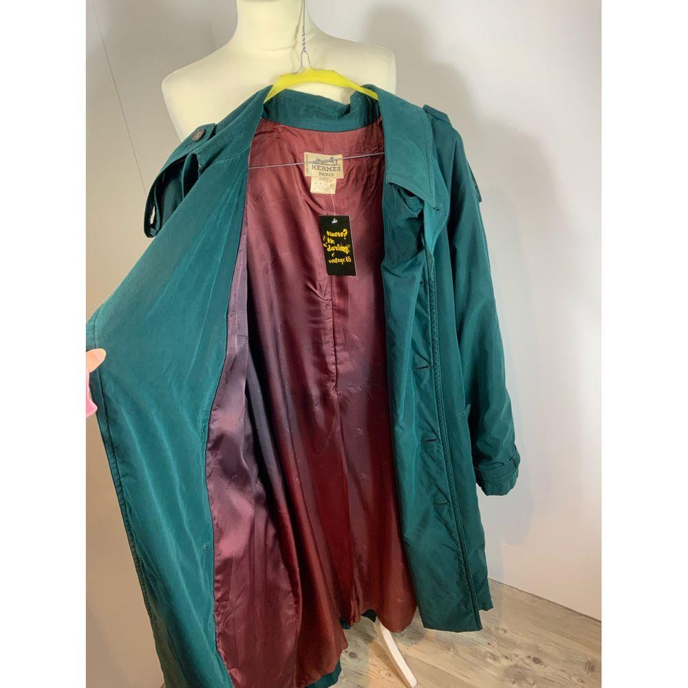 Hermès Polyester Trench Coat in Green

Hermes trench coat. 
In polyester and nylon. Very soft fabric. 
Lined (streaked as in the photo). 
It has 2 external and 1 internal pockets. 
The buckle of the belt and the sleeve are slightly damaged. [[2] ]