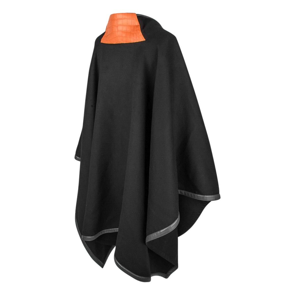 Guaranteed authentic Petite h Hermes black cashmere poncho.
Trimmed throughout with gray lambskin leather.
Poncho has Abricot matte alligator accent at rear of neck. 
Front kangaroo pockets are lined in silk scarf print.
An exquisite and practical