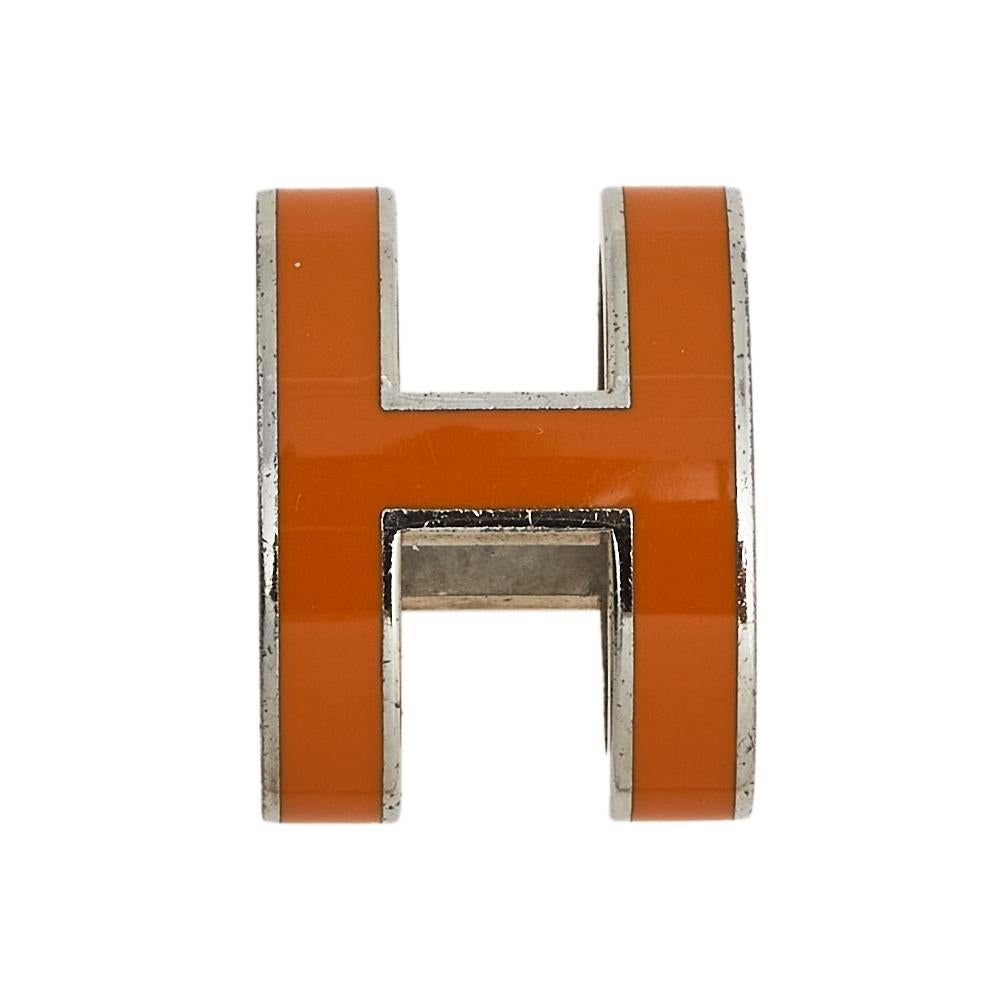This simple and dainty Pop H pendant from the house of Hermes is centered with an H-shaped pendant coated with orange lacquer. This simple yet elegant piece is secured is sculpted with palladium plated metal and looks best when styled with