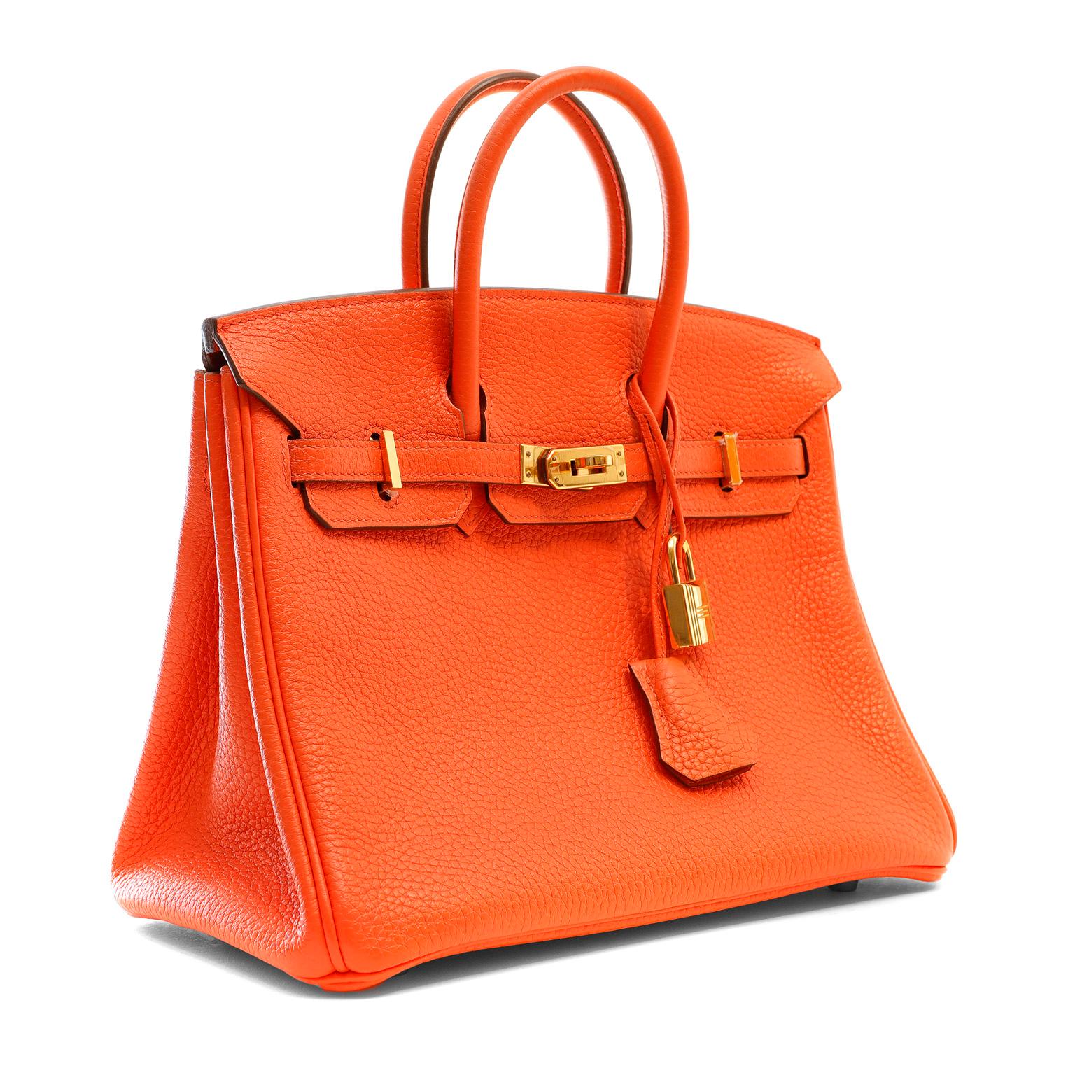 This authentic Hermès Poppy Orange Togo 25 cm Birkin is in pristine unworn condition with the protective plastic on the hardware.  A vibrant orange with a pinky undertone, it is perfectly paired with warm gold hardware.

Togo is scratch resistant