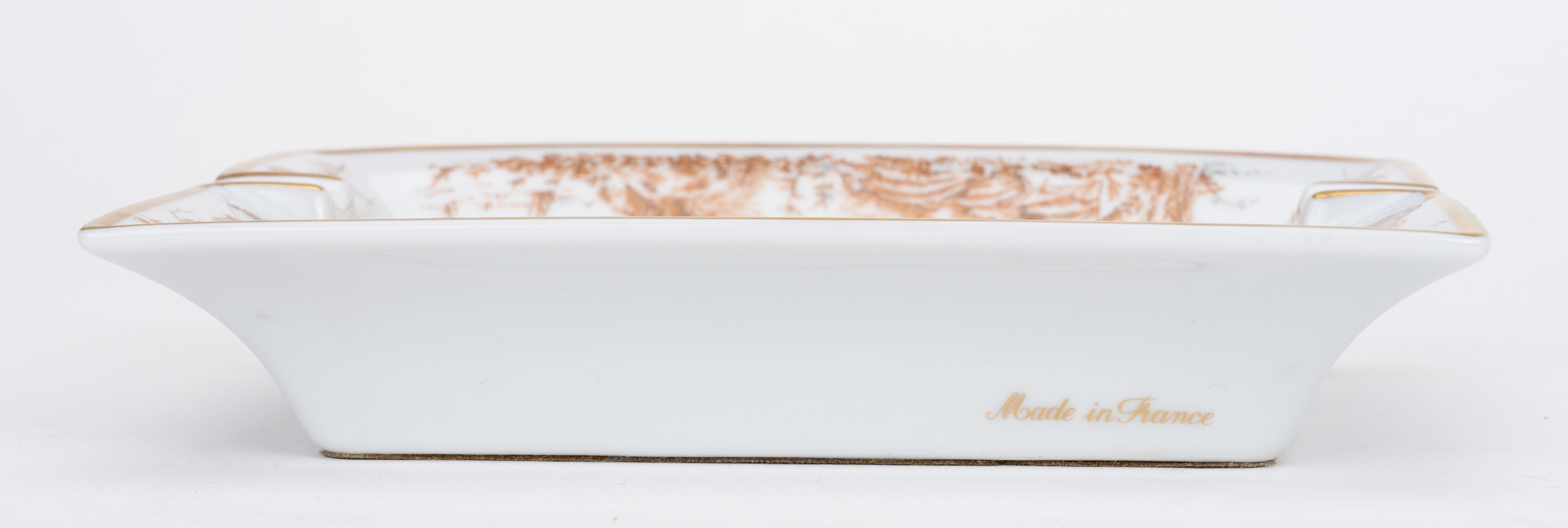 Hermès gold and white porcelain ashtray with wild boar design. Minor wear on back suede.