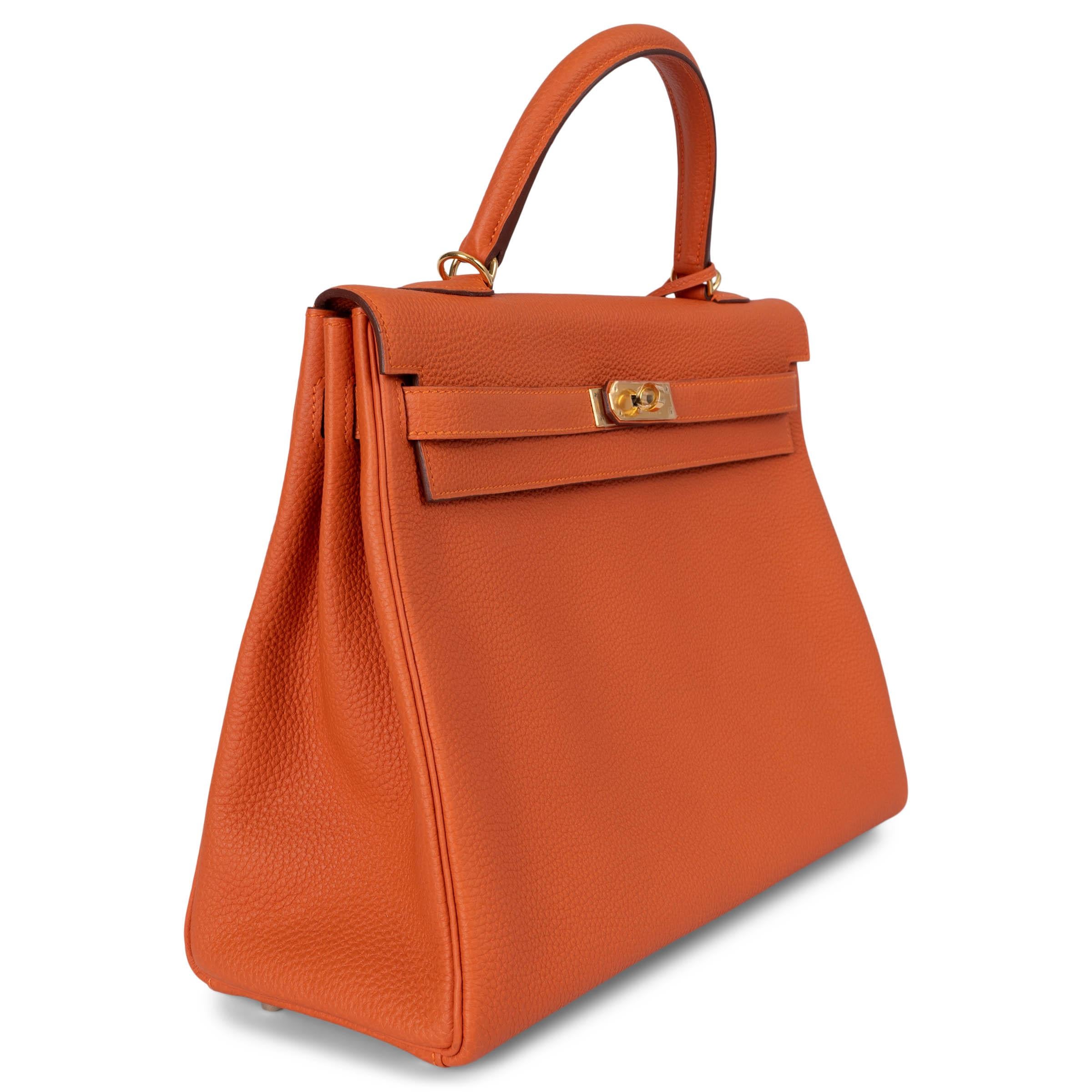 Bolso Hermès Kelly 35 Retourne 100% auténtico en piel Potiron (naranja calabaza) Taurillon Clemence con herrajes dorados. Forrado en piel de cabra naranja, con dos bolsillos abiertos delante y un bolsillo con cremallera detrás. A estrenar. Juego