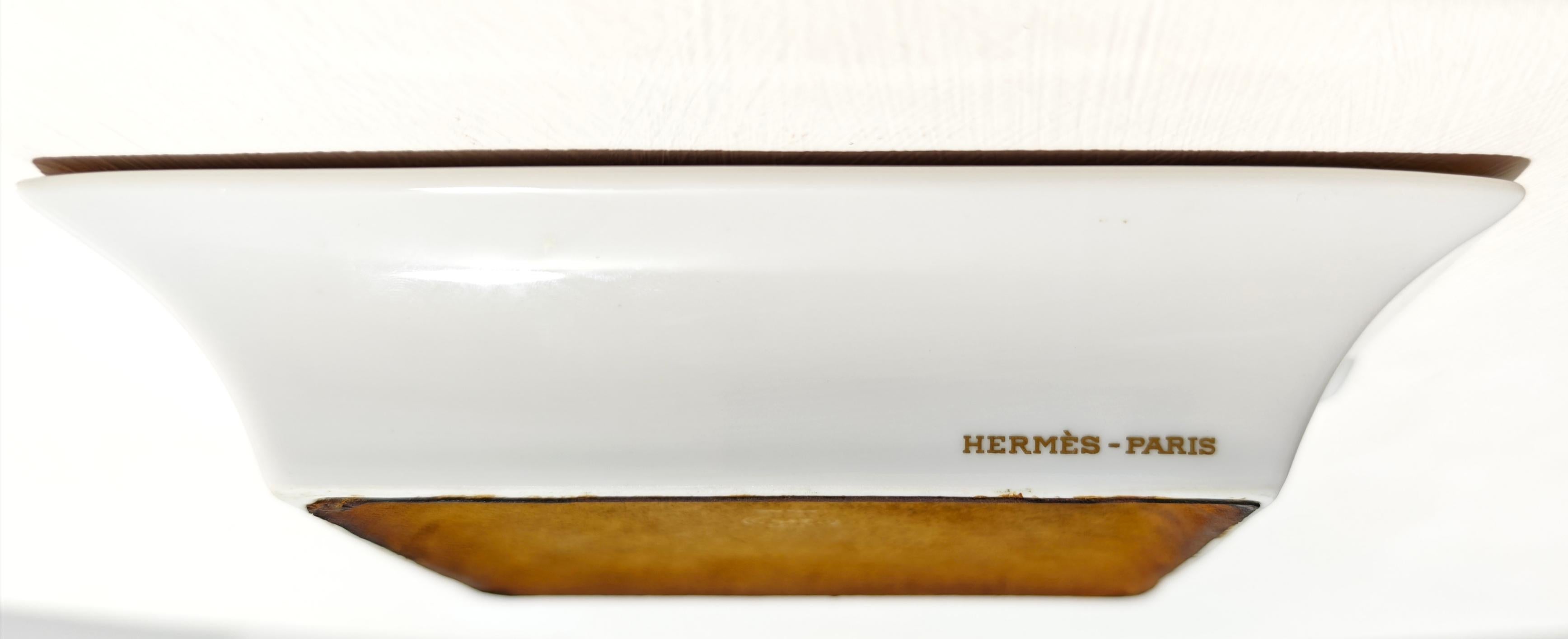 Eleganter, sammelwürdiger Porzellan-Aschenbecher von Hermès, der einen langhaarigen Terrier in einer naturalistischen Umgebung darstellt. Der Rand ist mit Skizzen aus der Natur, darunter Dachse und Füchse, in satten Bernstein- und Schwarztönen