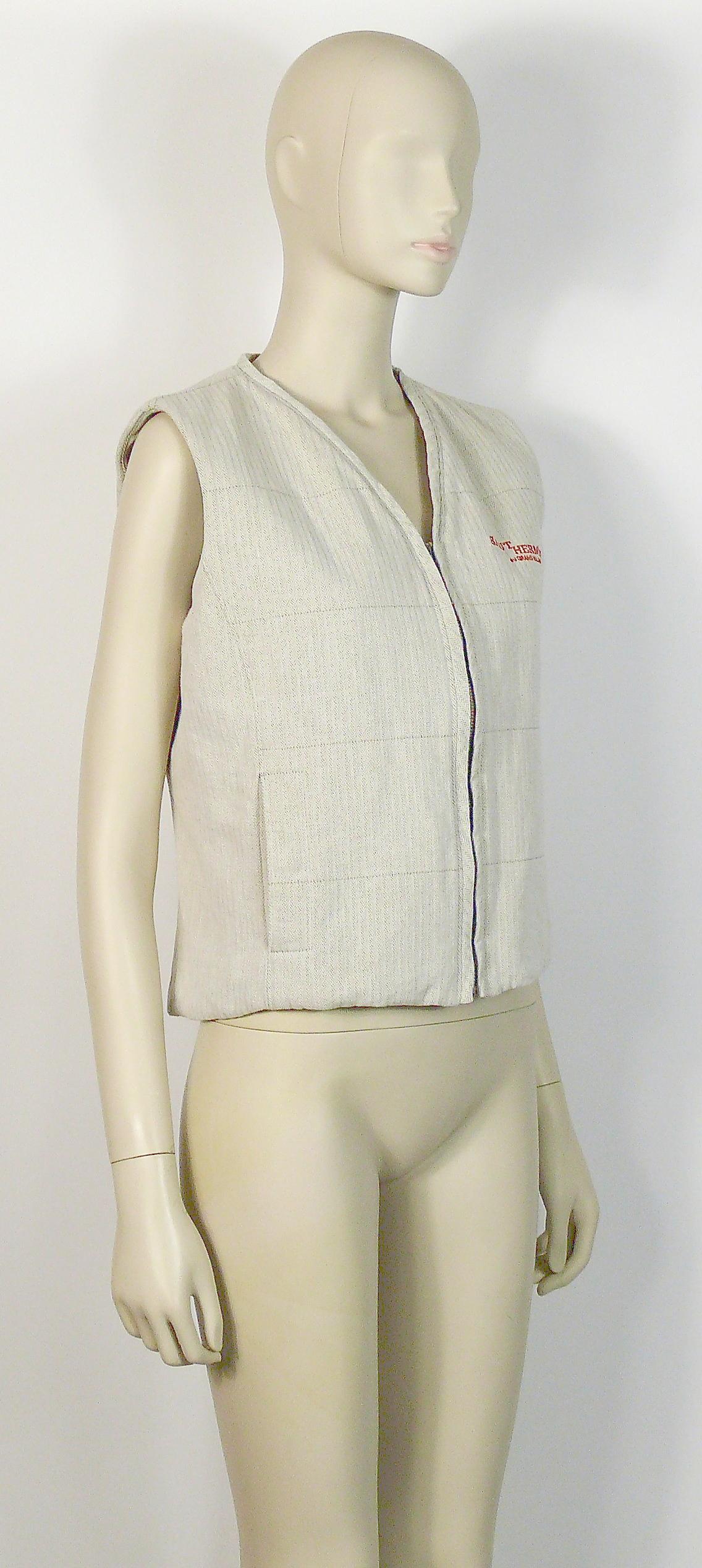 HERMES promotional beige herringbone canvas vest featuring a large iconic orange color clou de selle HERMES SELLIER patch on the back and SAUT HERMES AU GRAND PALAIS PARIS on front.

Front zip closure.
Two pockets with snap closure.
No lining.
Made