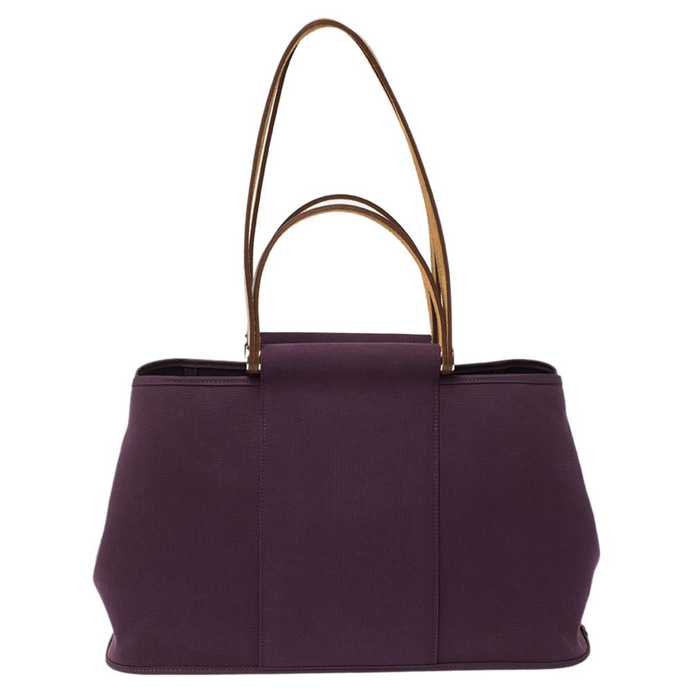 The Cabag Elan tote by Hermès has a unique design. Crafted from purple toile canvas, this tote has a spacious interior, silver-tone hardware, and a slightly relaxed silhouette. The two top handles and two shoulder handles act as the highlight of the