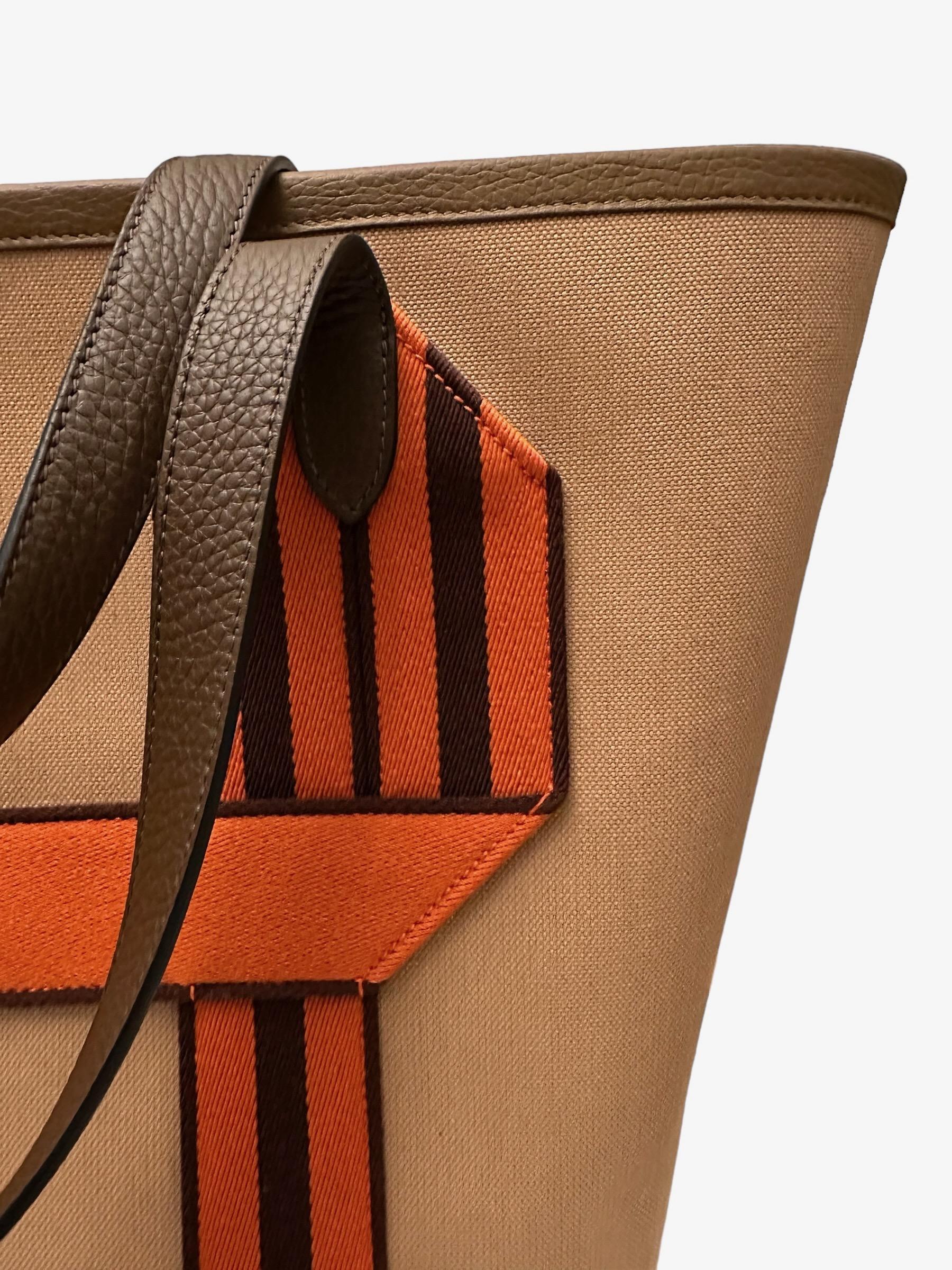 This pre-owned but new tote bag from the house of Hermès is crafted in military canvas, taurillon Clemence leather and Wooly canvas with handles. It features a large compartment, a zipped interior back pocket and a striped 
