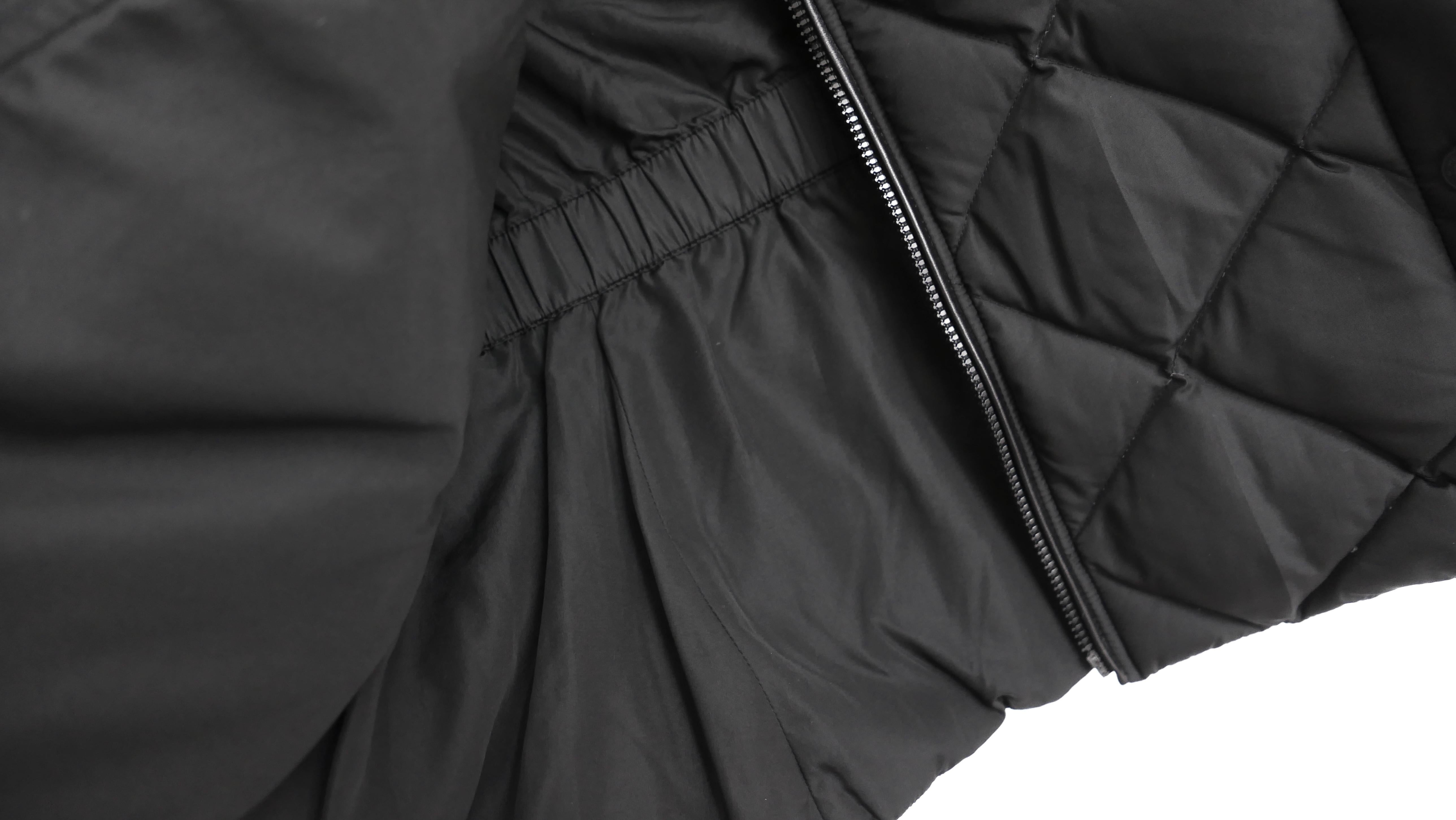 Wunderschöne ärmellose Hermes Steppjacke mit Gilet. Ungetragen. Aus glattem schwarzem Polyester mit Puffersteppmuster und  Füllung aus weißen Gänsedaunen. Mit Gummiplakette auf der Vorderseite, lederbesetztem Reißverschluss, geripptem Trichterhals