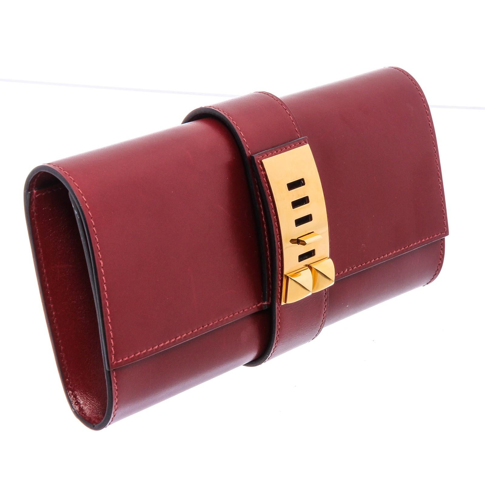 Red Box leather Hermès Medor 23 clutch with gold-plated hardware, tonal leather interior, single interior slit pocket and belted slide-lock closure at exterior. 20534MSC.