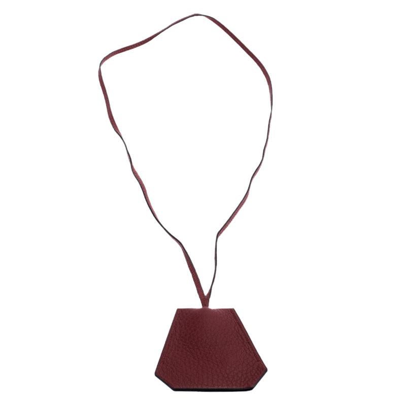 A stroke of luck for collector's and Hermes fans is this necklace. It is crafted from red Clemence leather and designed as a clochette usually seen with Hermes' bags. The pendant is held by a string and it hides two silver-tone rings.

Includes: