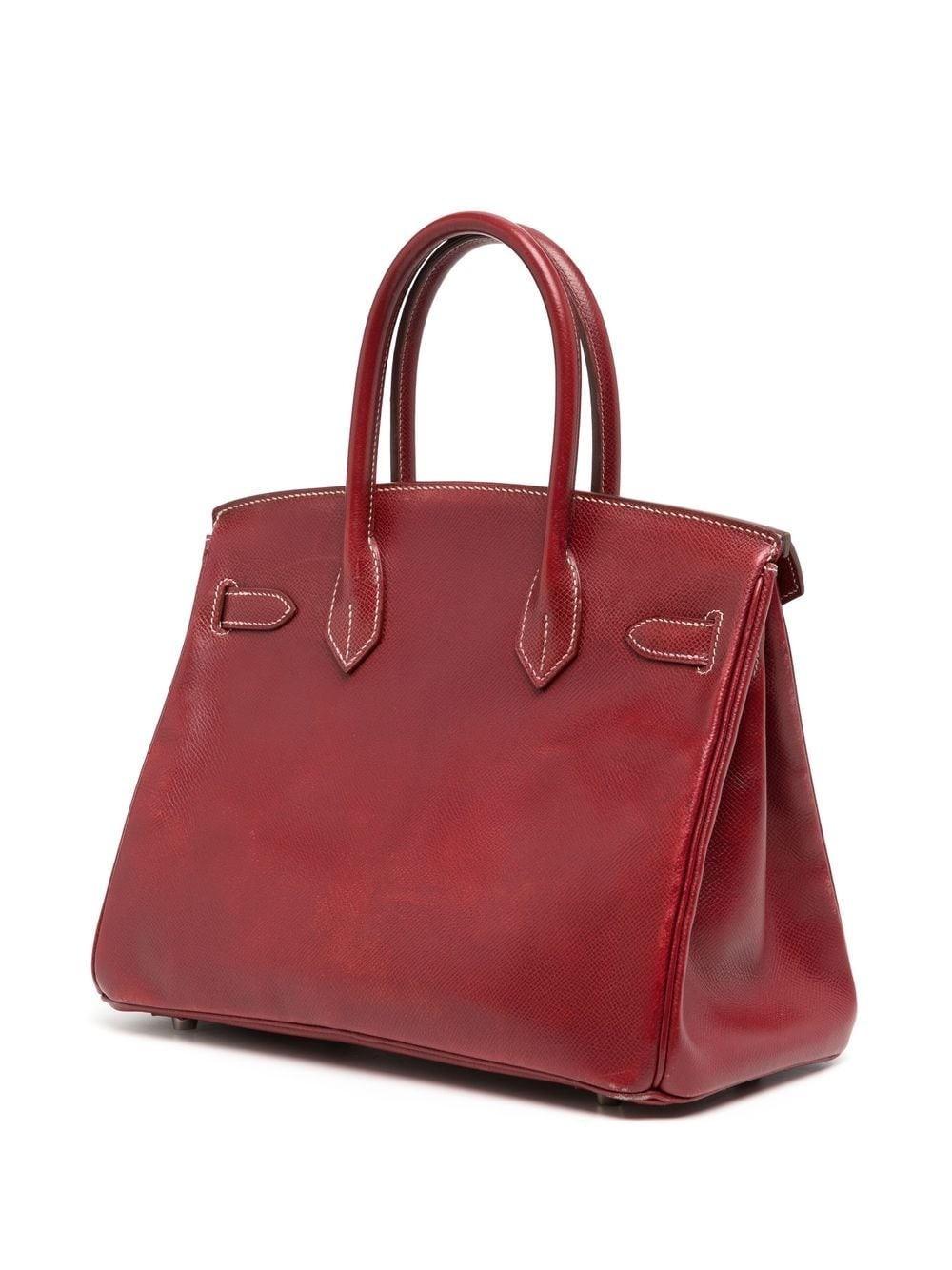 In a beautiful red burgundy colour, the courchevel leather adds the perfect balance of shine and texture for this 30cm Birkin. Made in 2001, this piece has truly maintained its quality, however it does show some wear on the bottom corners. Some