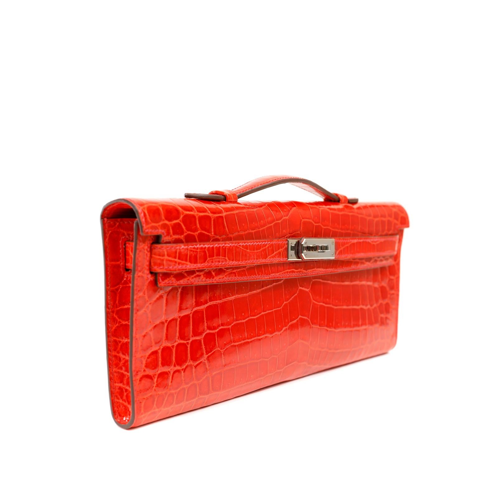 Diese authentische Hermès Vivid Red Crocodile Kelly Cut Clutch ist in tadellosem Zustand.  Die Kelly Cut wird von geschickten Handwerkern in Handarbeit hergestellt und ist eine äußerst seltene Tasche aus exotischem Niloticus-Krokodilleder mit