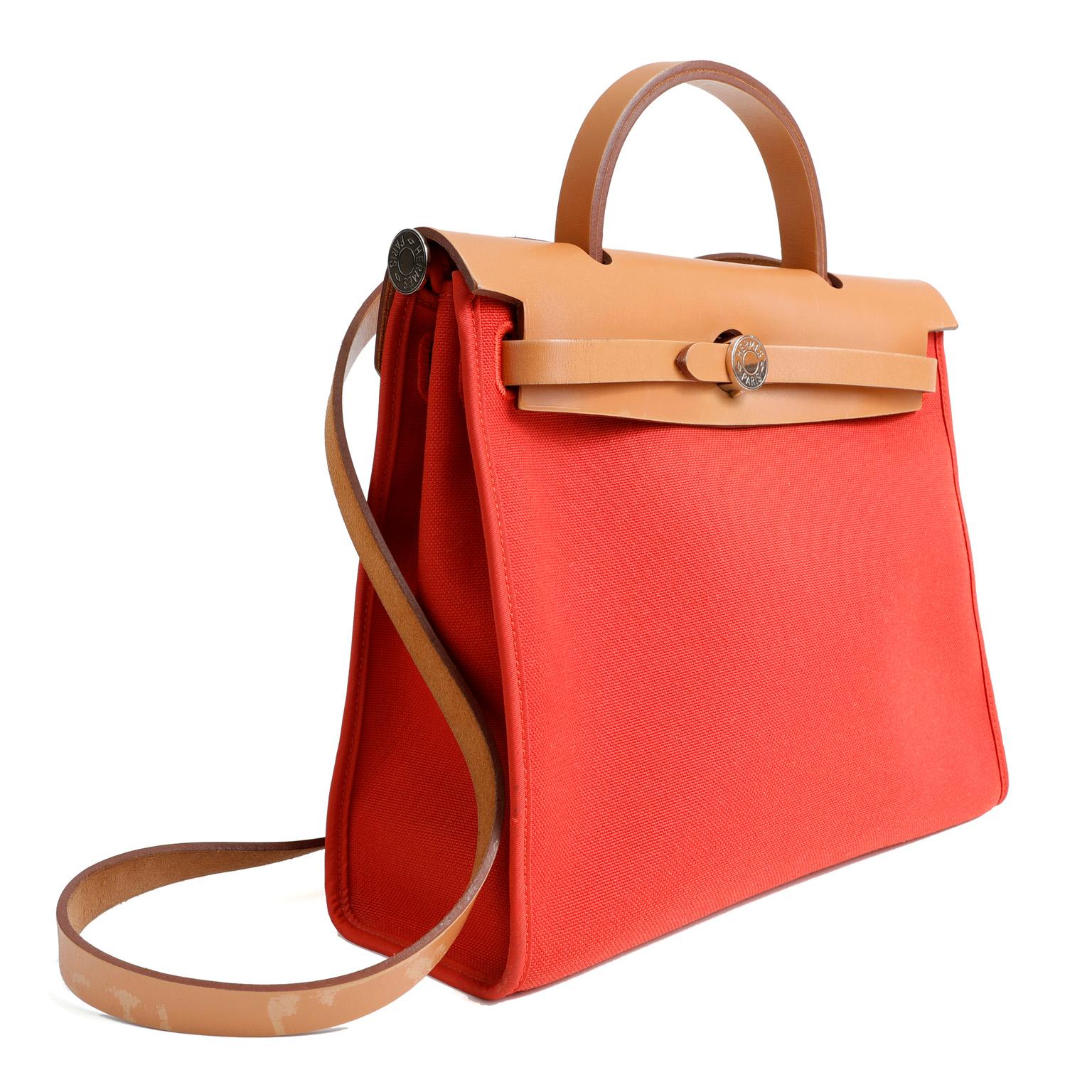 This authentic Hermès Red Herbag Zip 39 is in pristine condition, appearing never carried.     The Her Bag is comprised of sturdy wearable canvas fabric with a durable Vache Hunter leather top.  It has a similar look to the Kelly but with a far less