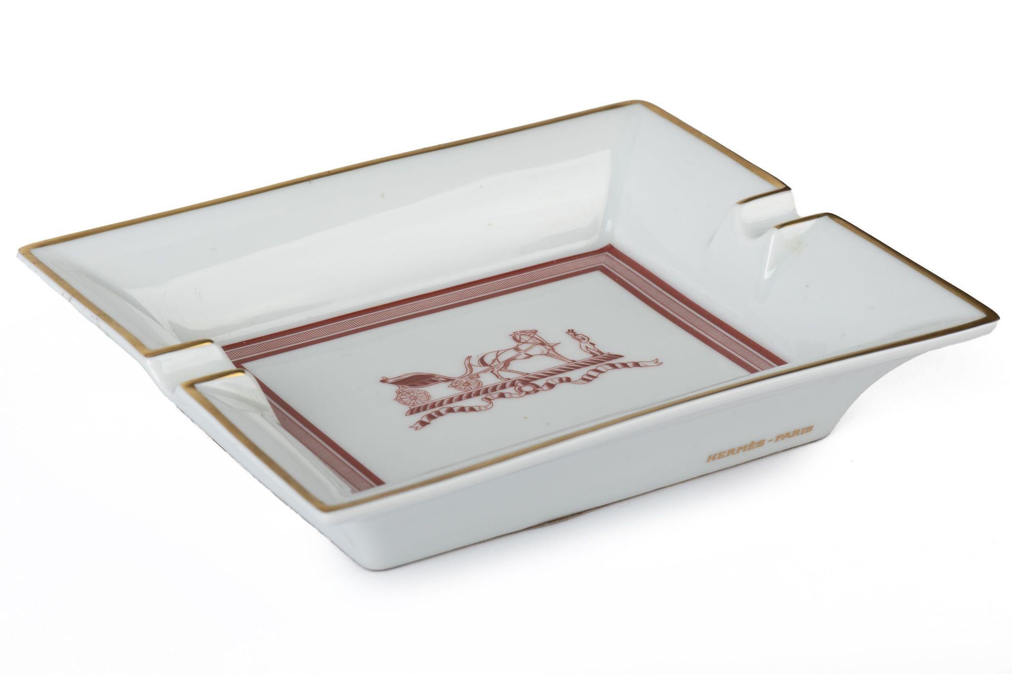 Hermès signature ashtray in white with a horse carriage and a charioteer design in red. Suede stamped bottom.