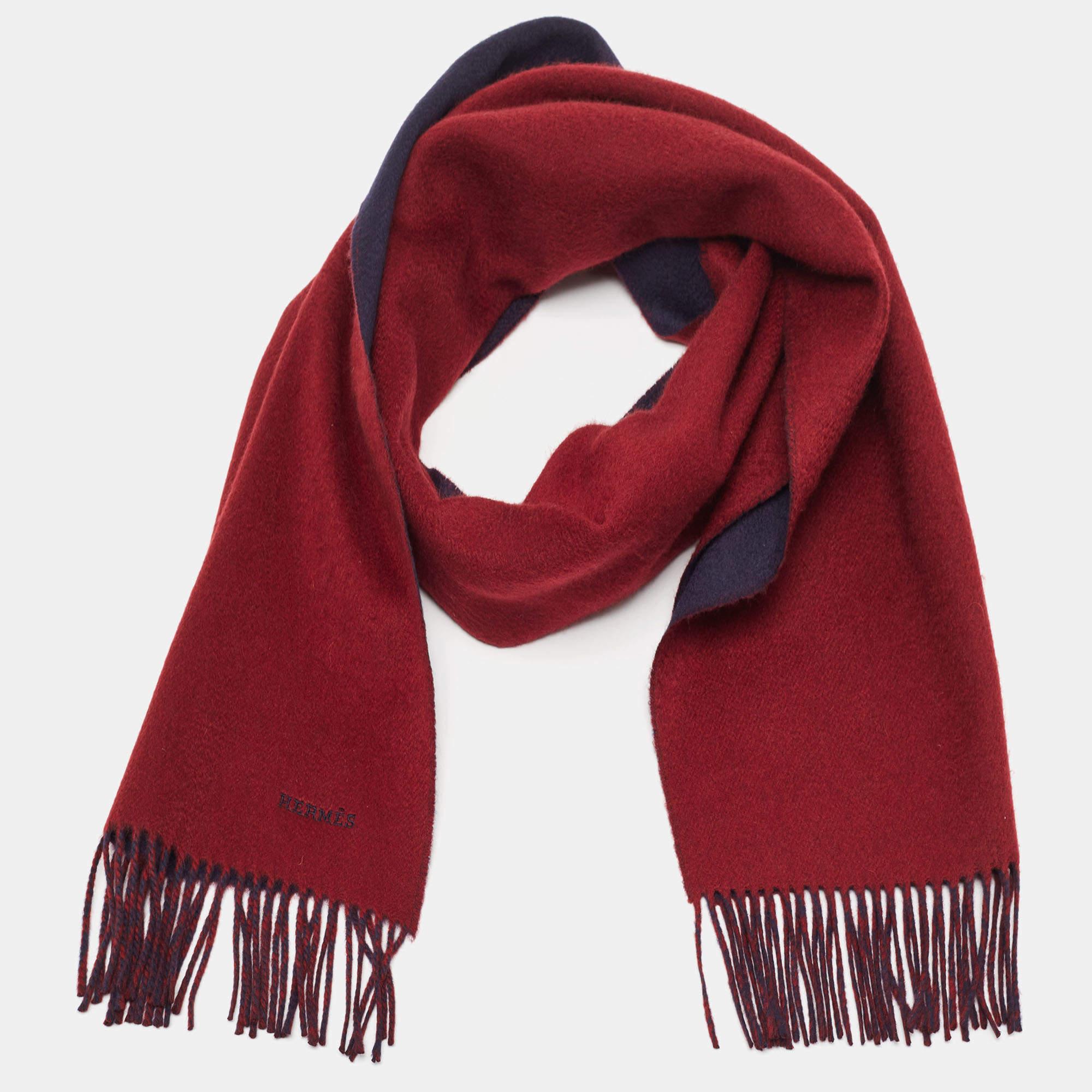 The Hermès muffler is a luxurious accessory crafted from sumptuous cashmere. Its vibrant red and navy blue hues create a striking contrast, while the fringed edges add a touch of elegance. This meticulously designed muffler exemplifies timeless