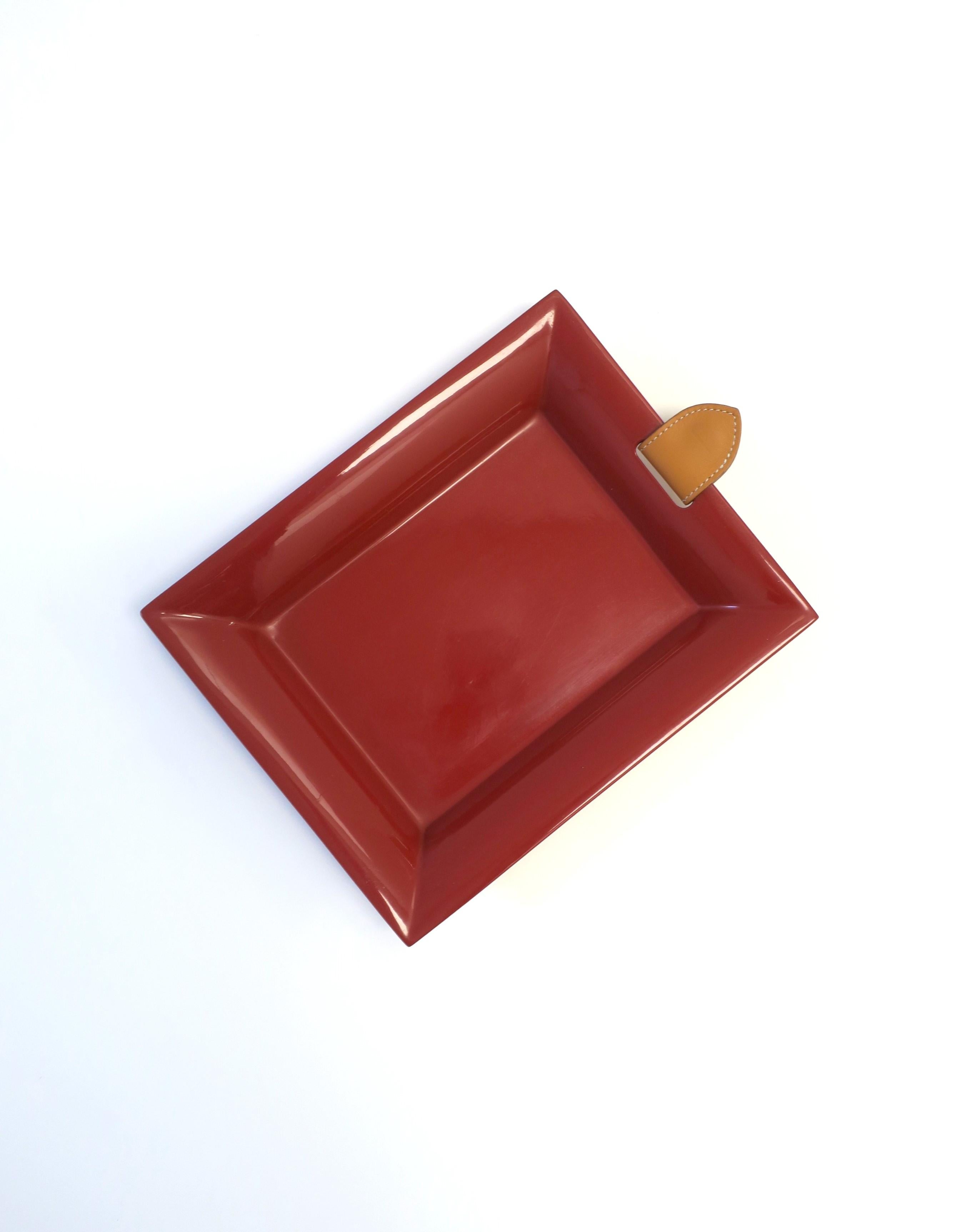 Ein wunderschönes, burgunderrot lackiertes Tablett mit braunem Leder von Maison Hermes, ca. Ende des 20. Jahrhunderts, Frankreich. Das Stück ist aus lackiertem Birnbaumholz mit einer hellbraunen Kalbslederlasche mit Sattelnaht und der