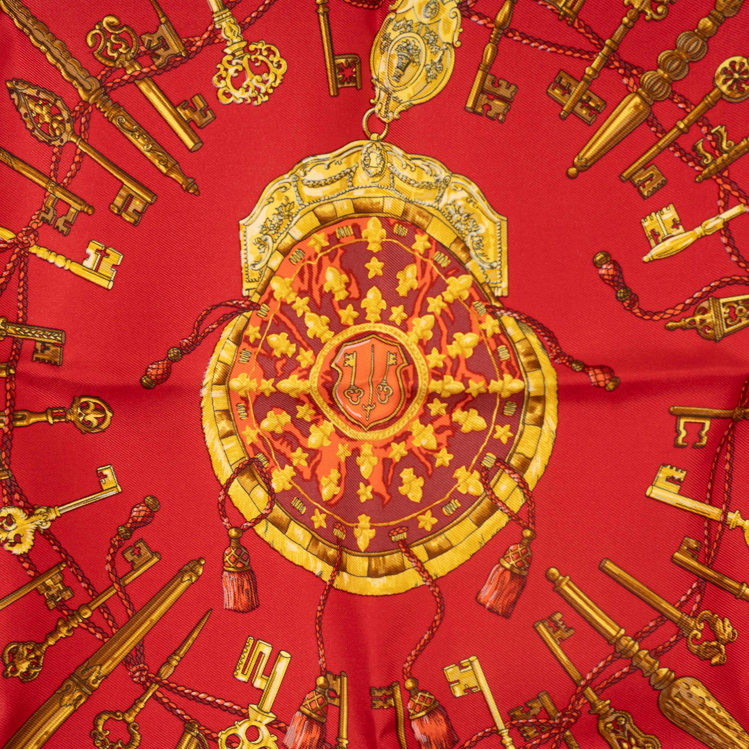 This 100% authentic Hermès Les Cles 45 Twill Pocket Square is crafted from luxurious red silk (100%), featuring intricate details in gold, orange, and brown. The timeless design showcases the iconic Les Cles motif, adding a touch of elegance and