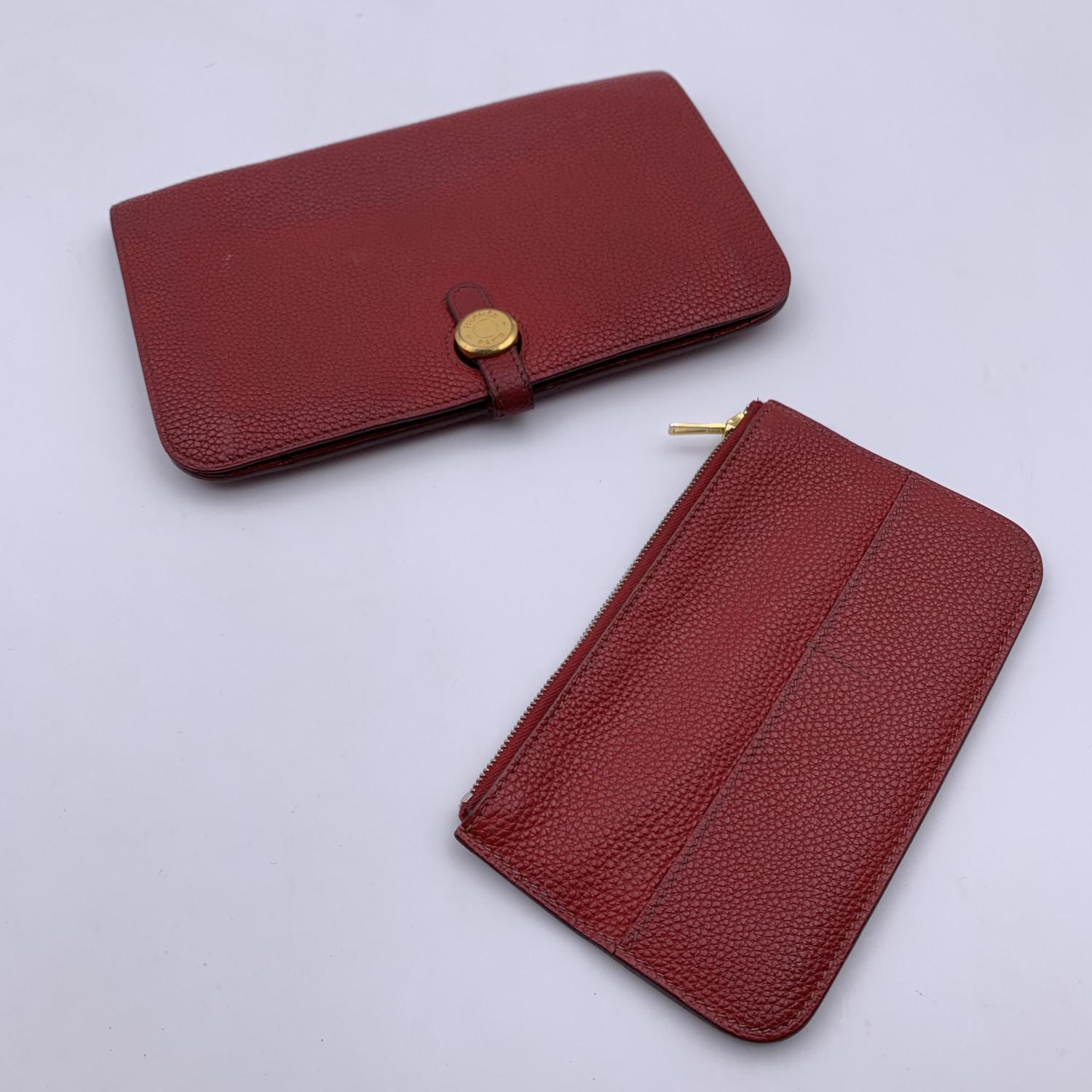 Hermes Dogon Duo wallet in red Togo leather. Bifold design with gold metal Clou de Selle closure. Red leather lining. Inside it has a removable coin purse with zip closure, five compartments for credit cards, a compartment for bill s and 2 open